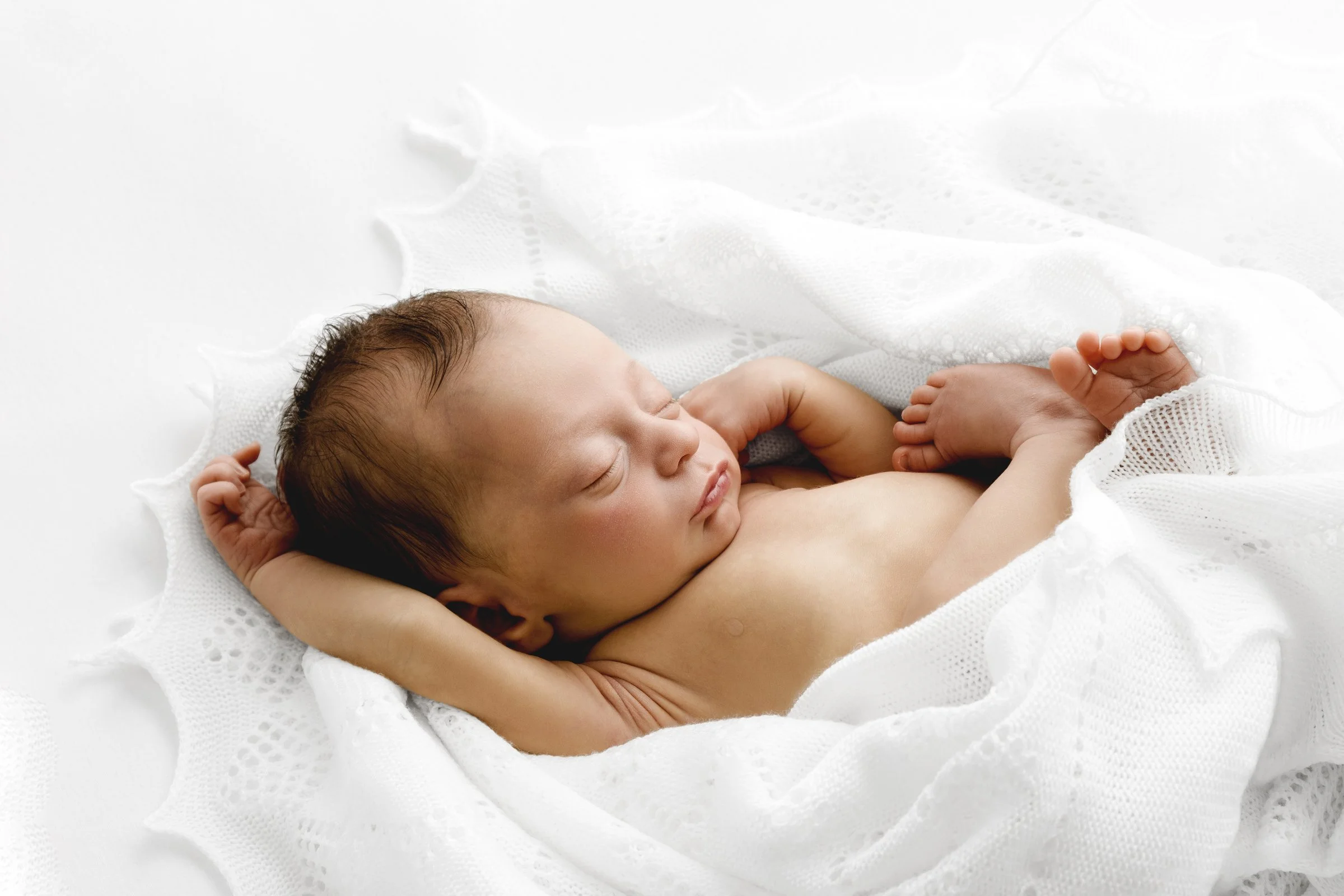 Newborn baby wrapped in white lace during calm studio session in Dundee