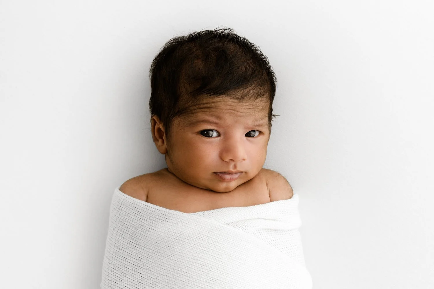 Sweet baby lying on their back making eye contact at a baby photography session