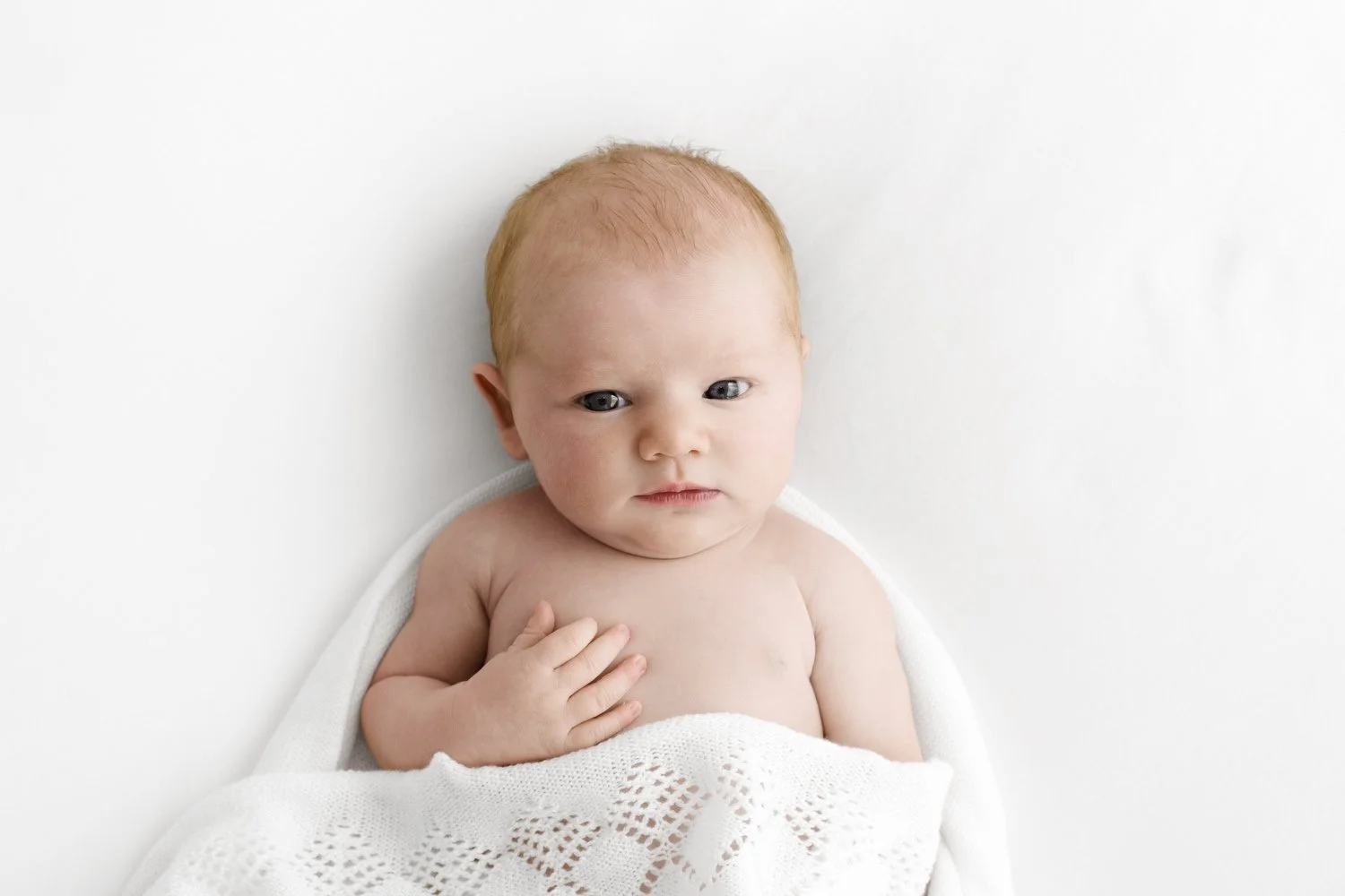 awake newborn in while shawl at natural photography session in dundee studio