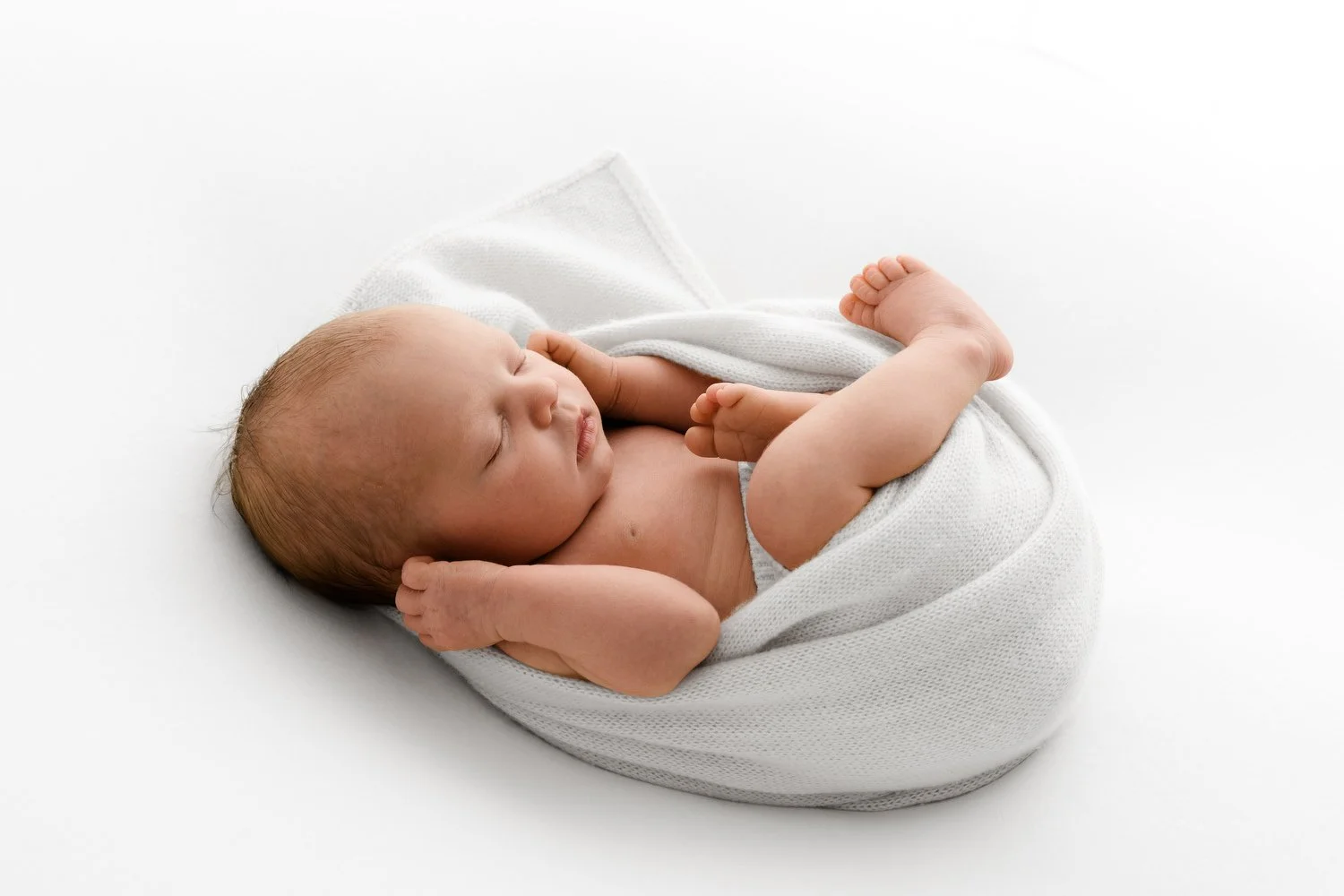 Contented newborn tucked in peacefully for a relaxed baby photoshoot in Dundee