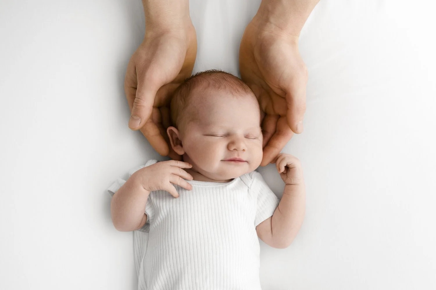 newborn sleeping with dads hands around his head at natural family and baby photoshoot