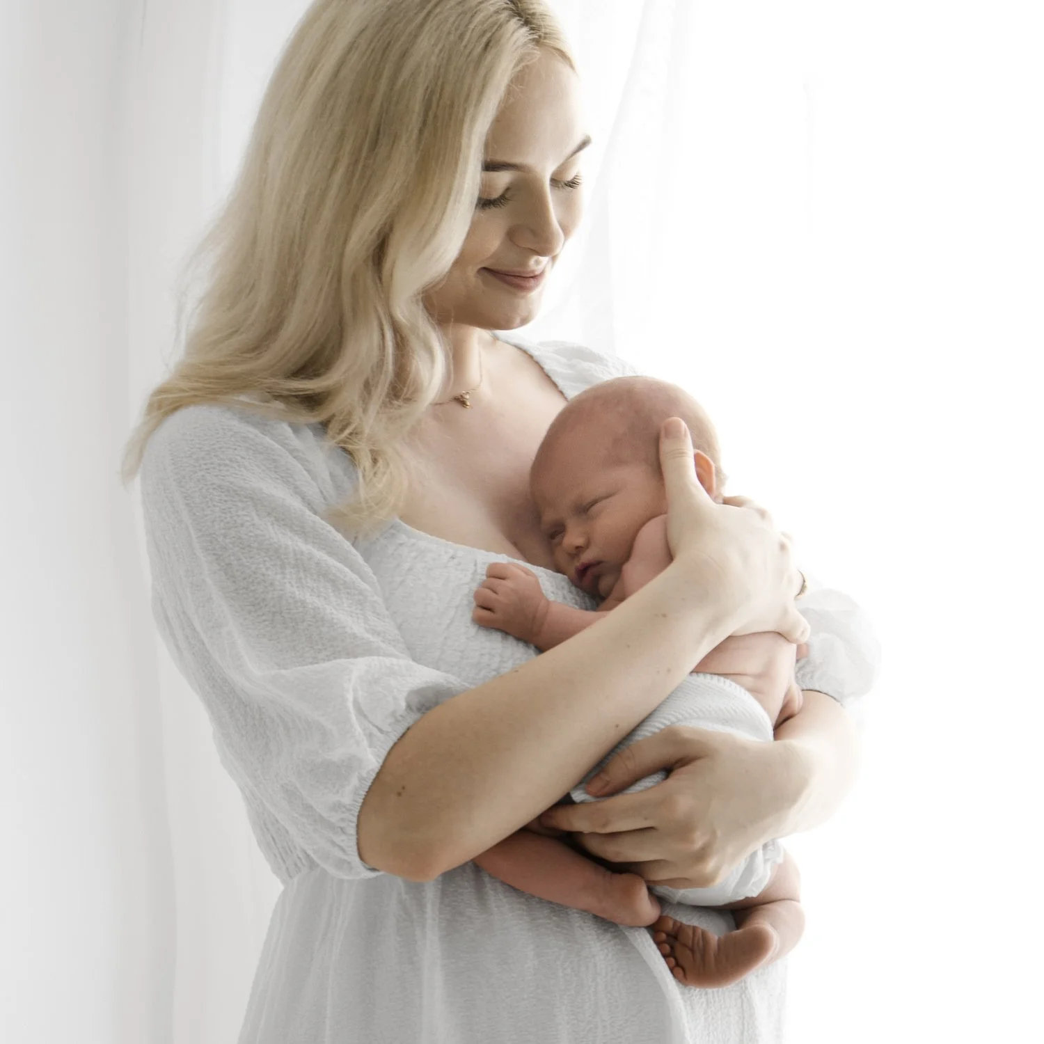 Mum in white dress holding her newborn during Dundee studio photoshoot