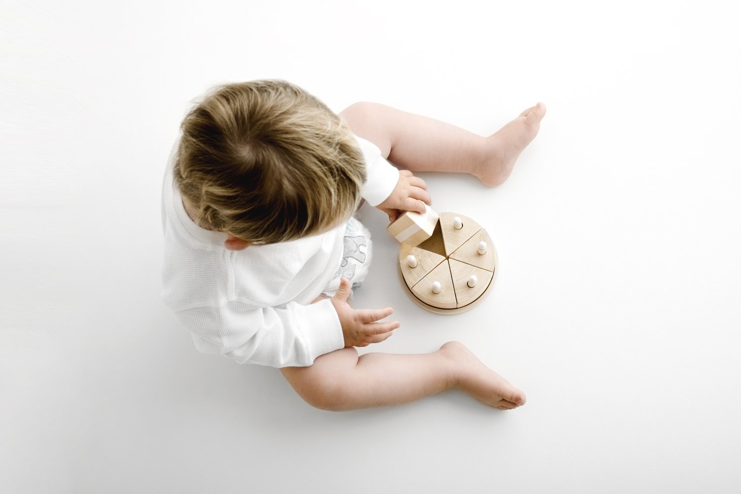 Overhead view of baby playing with wooden birthday cake and candles at first birthday photoshoot Mabel and Moose Dundee