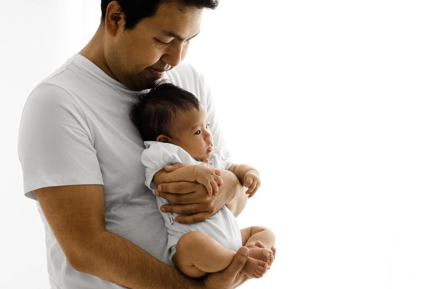 Father holding his three month old baby in white studio setting