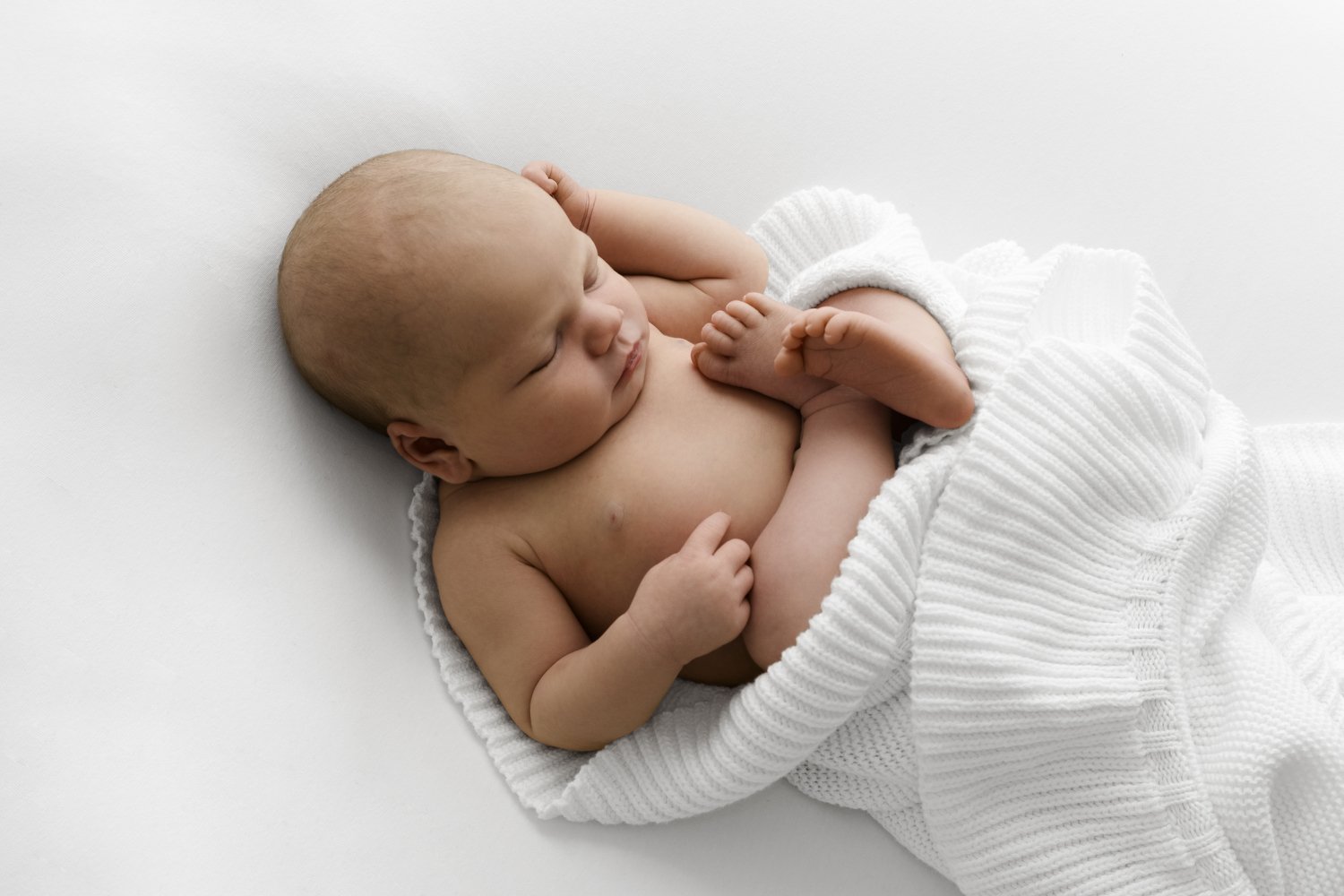 sleeping newborn baby wrapped in a white blanket