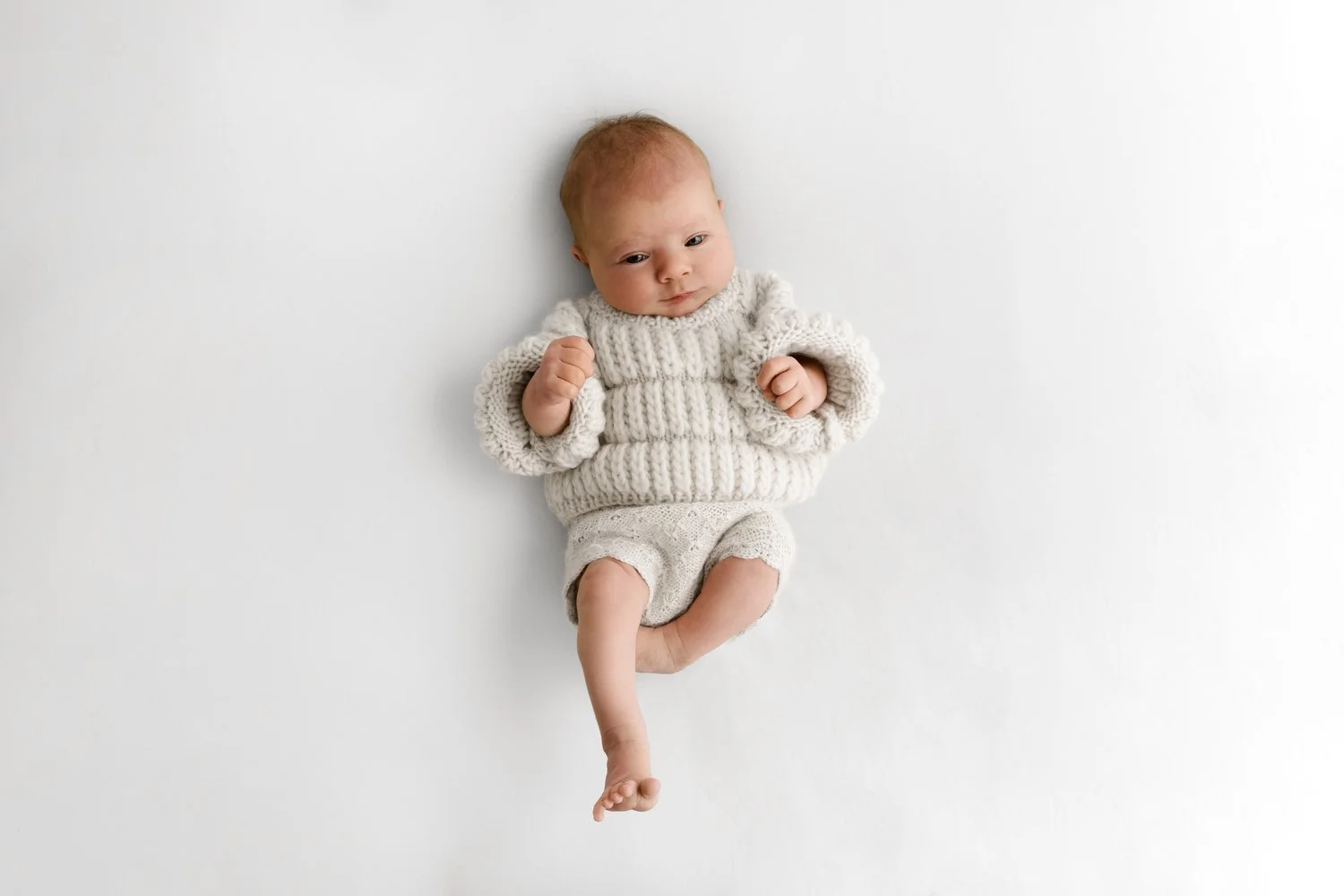 Newborn baby in Scandi style white knit with tiny bare feet at Mabel and Moose studio Dundee