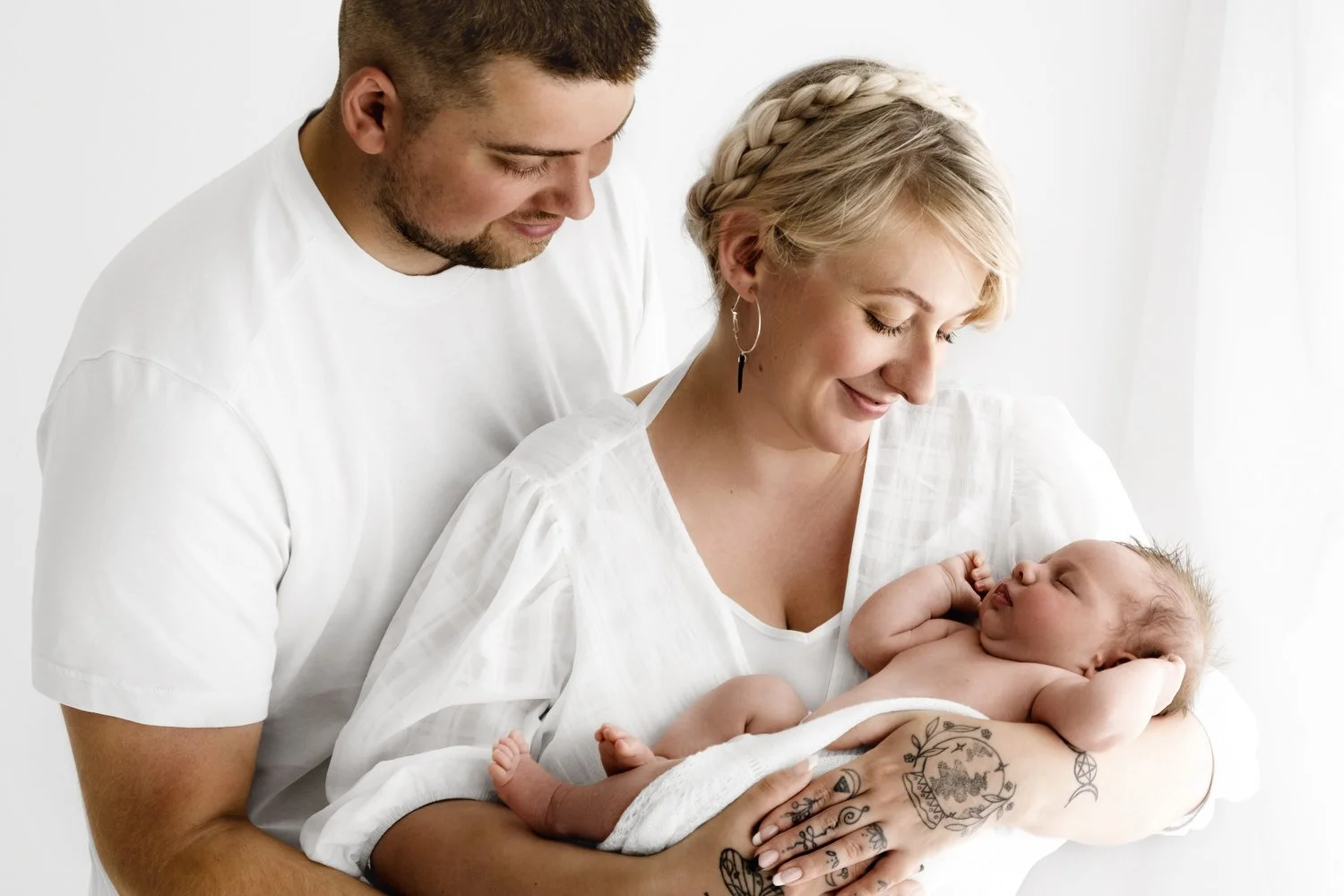 Newborn baby held by both parents in natural white studio in Dundee