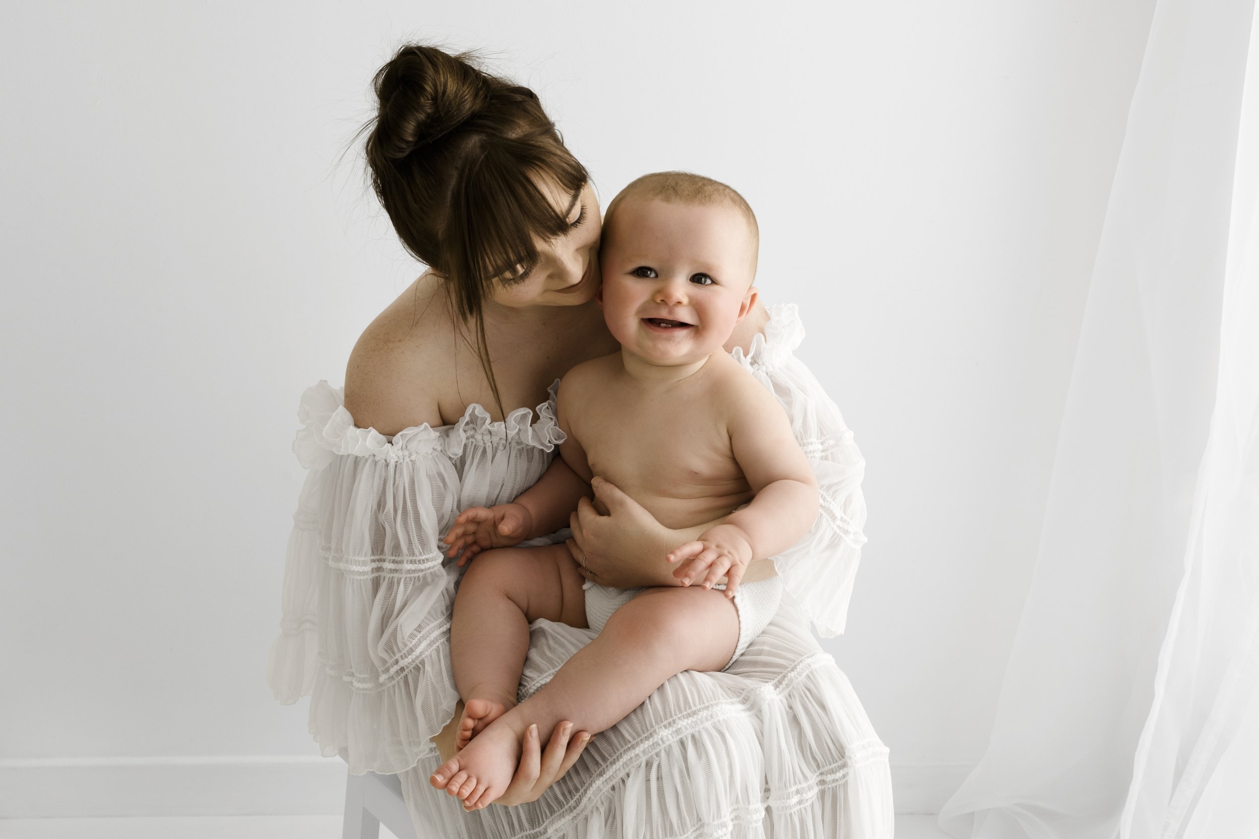 Mum in white dress holding laughing 7 month old baby during Dundee studio photoshoot