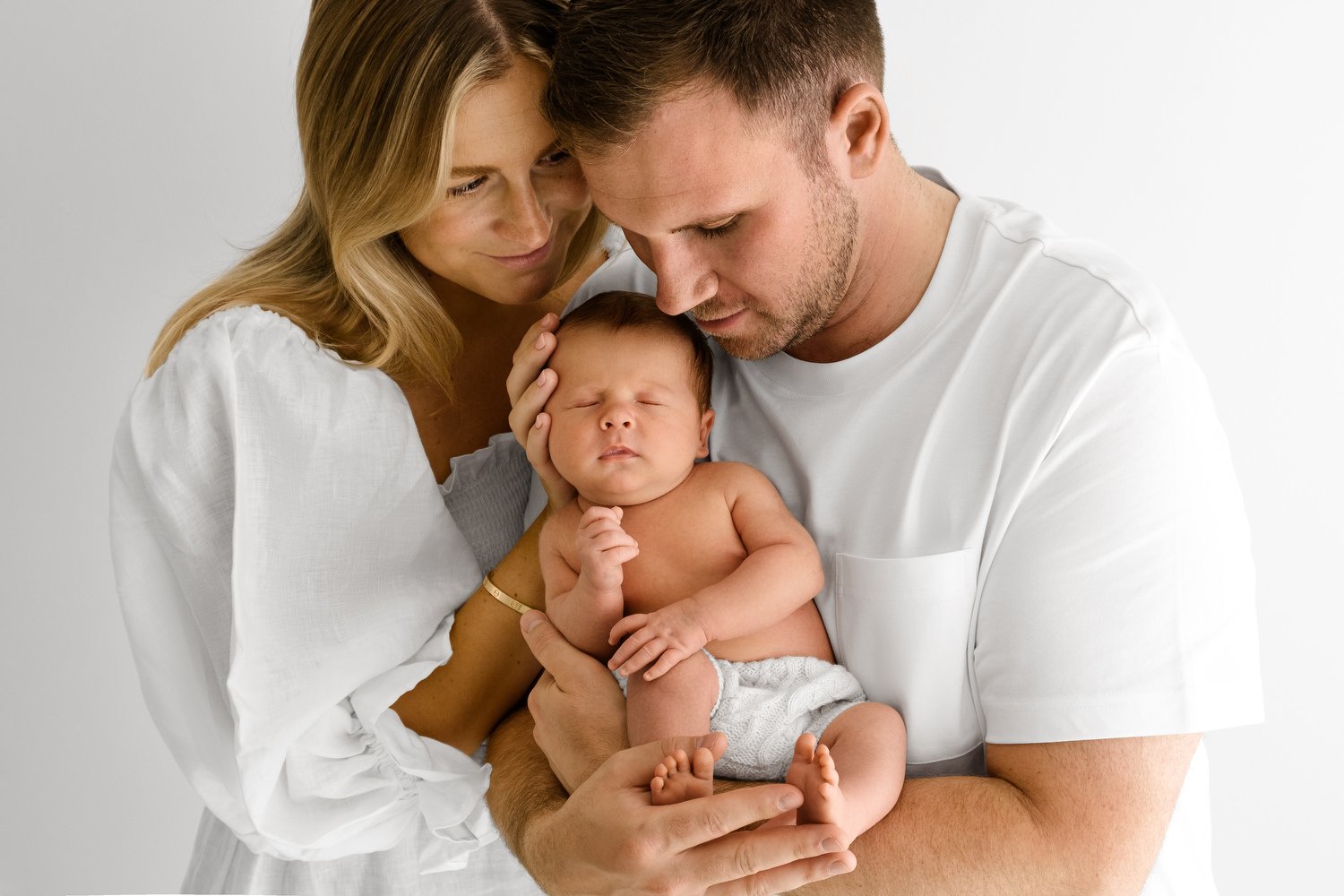 Parents cradling 14 day old newborn baby at Mabel and Moose studio Monifieth Dundee