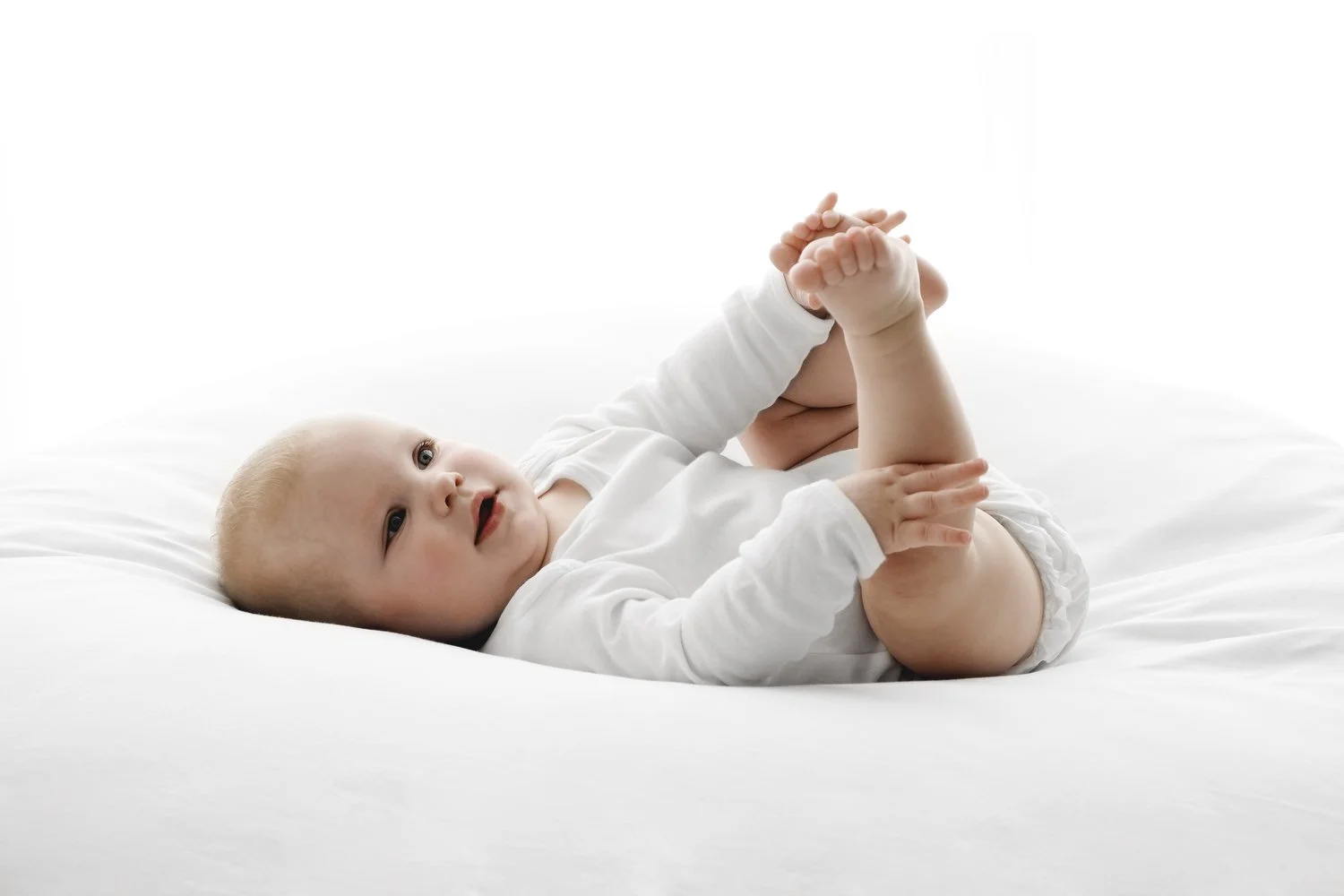 9 month old baby lying on back playing with her toes during baby photoshoot in Dundee