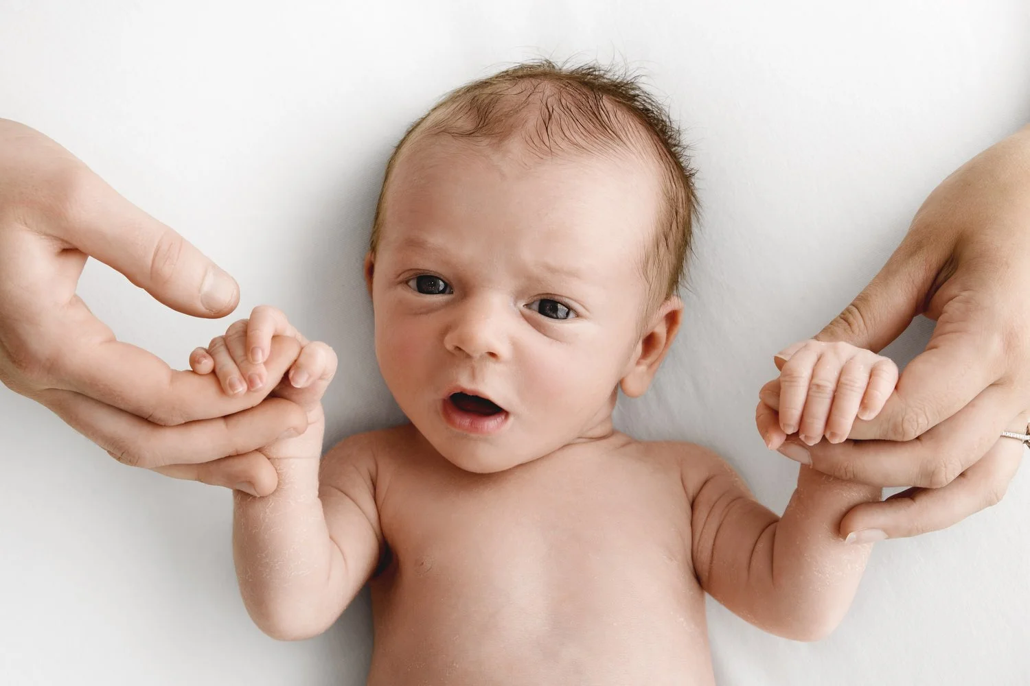 Newborn baby holding mum and dad’s hands during Dundee studio photoshoot