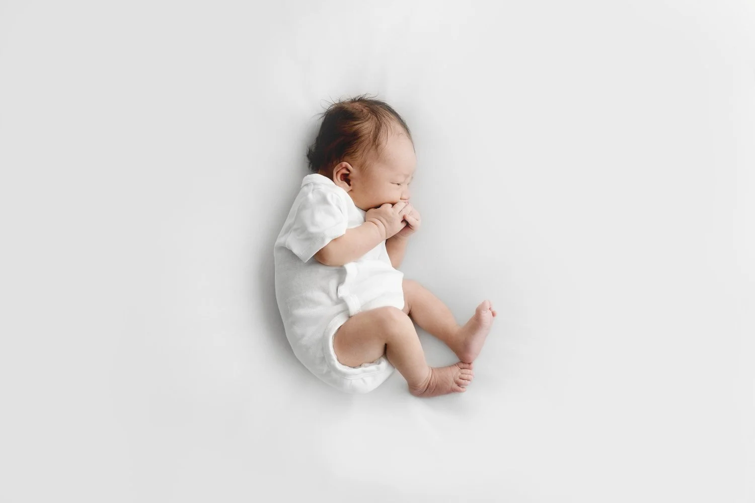 Newborn lying on side in white vest during natural Dundee studio photoshoot