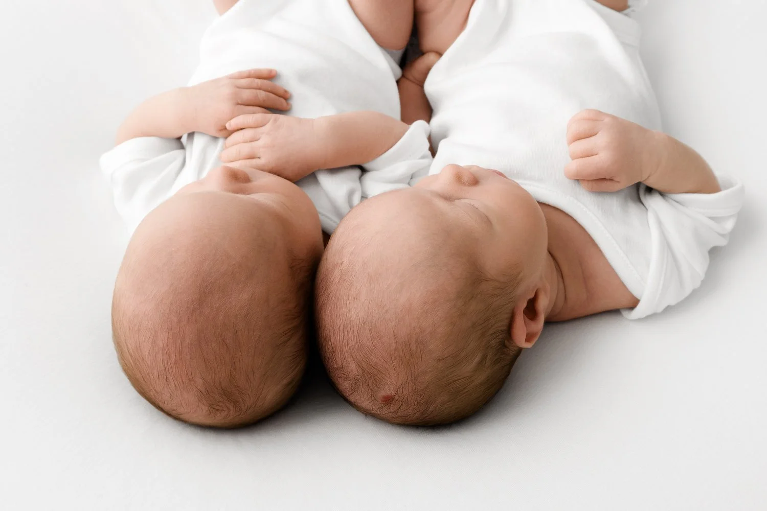 Close-up of twin newborn babies’ heads photographed in white studio setting