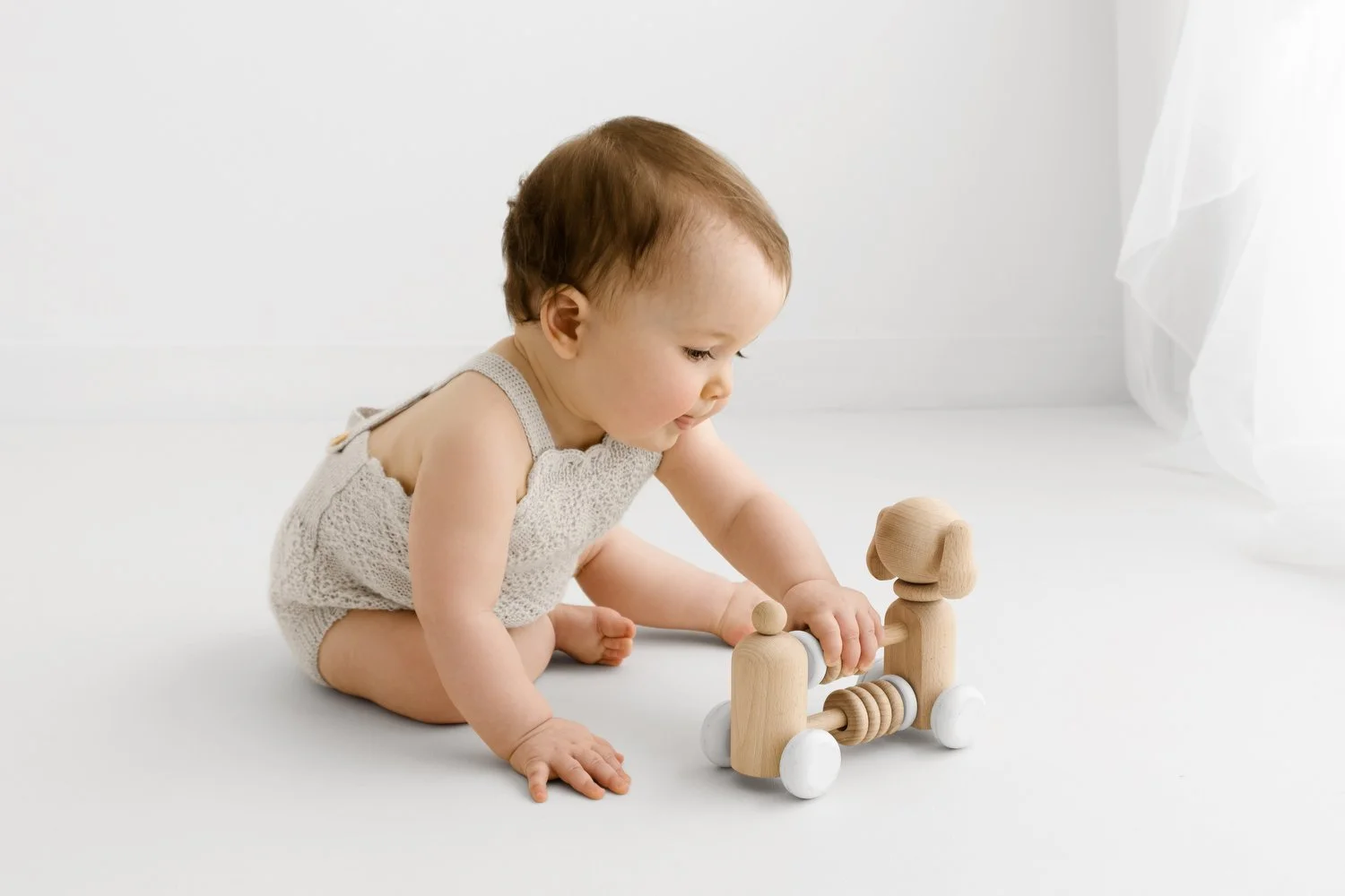 baby playing with wooden toy at Natural  baby photography at Mabel and Moose studio Monifieth Dundee