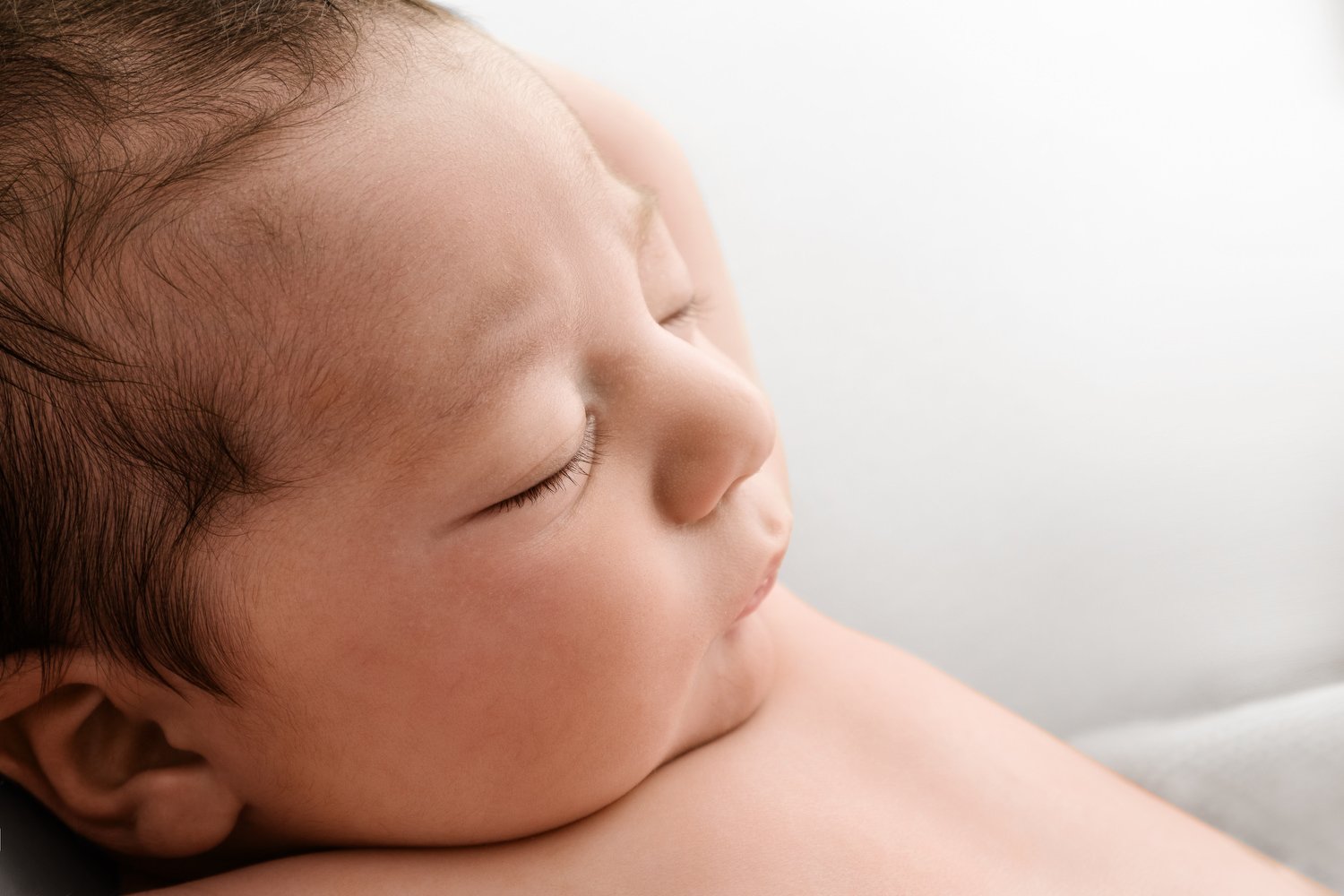 Side profile of newborn baby showing delicate forehead in natural light