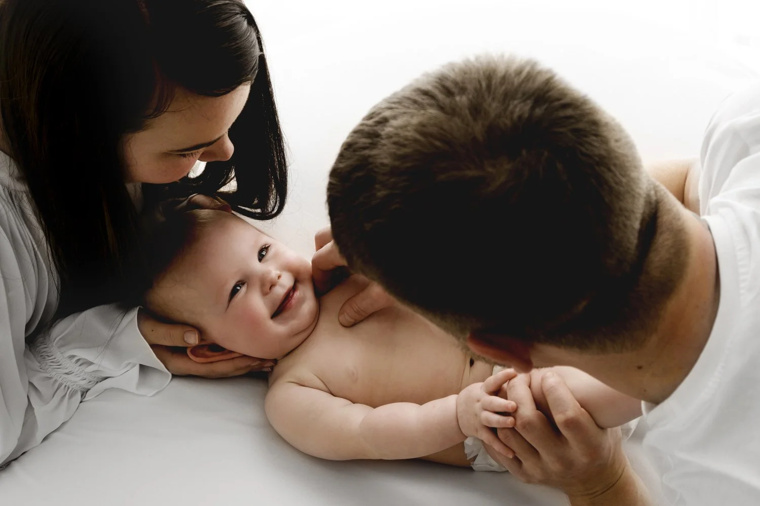 Mum and dad hugging their 9 month old baby during relaxed studio photoshoot in Dundee