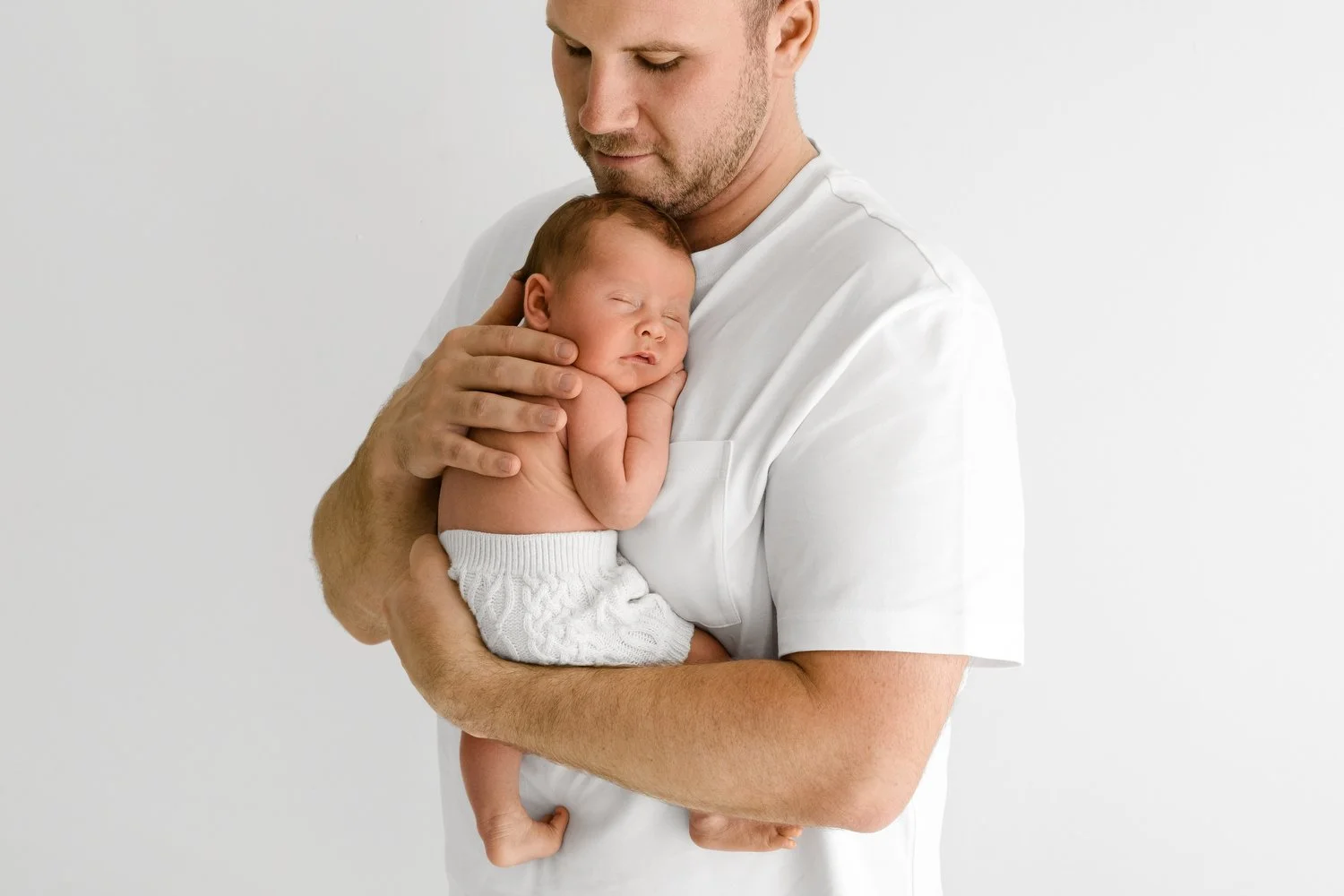 Dad in relaxed white t shirt holding newborn baby at Mabel and Moose photography studio Dundee