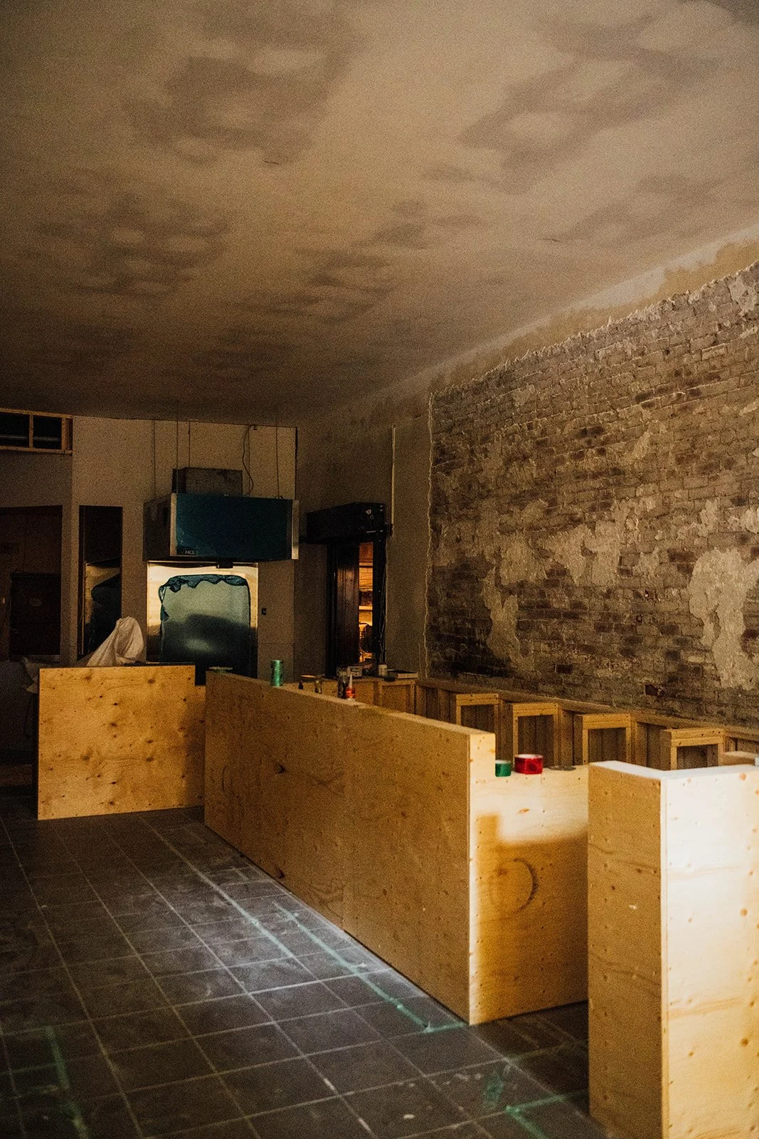  The bar takes shape in raw plywood, the exposed brick wall and chalked floor grid hinting at the room that would soon come to life. 