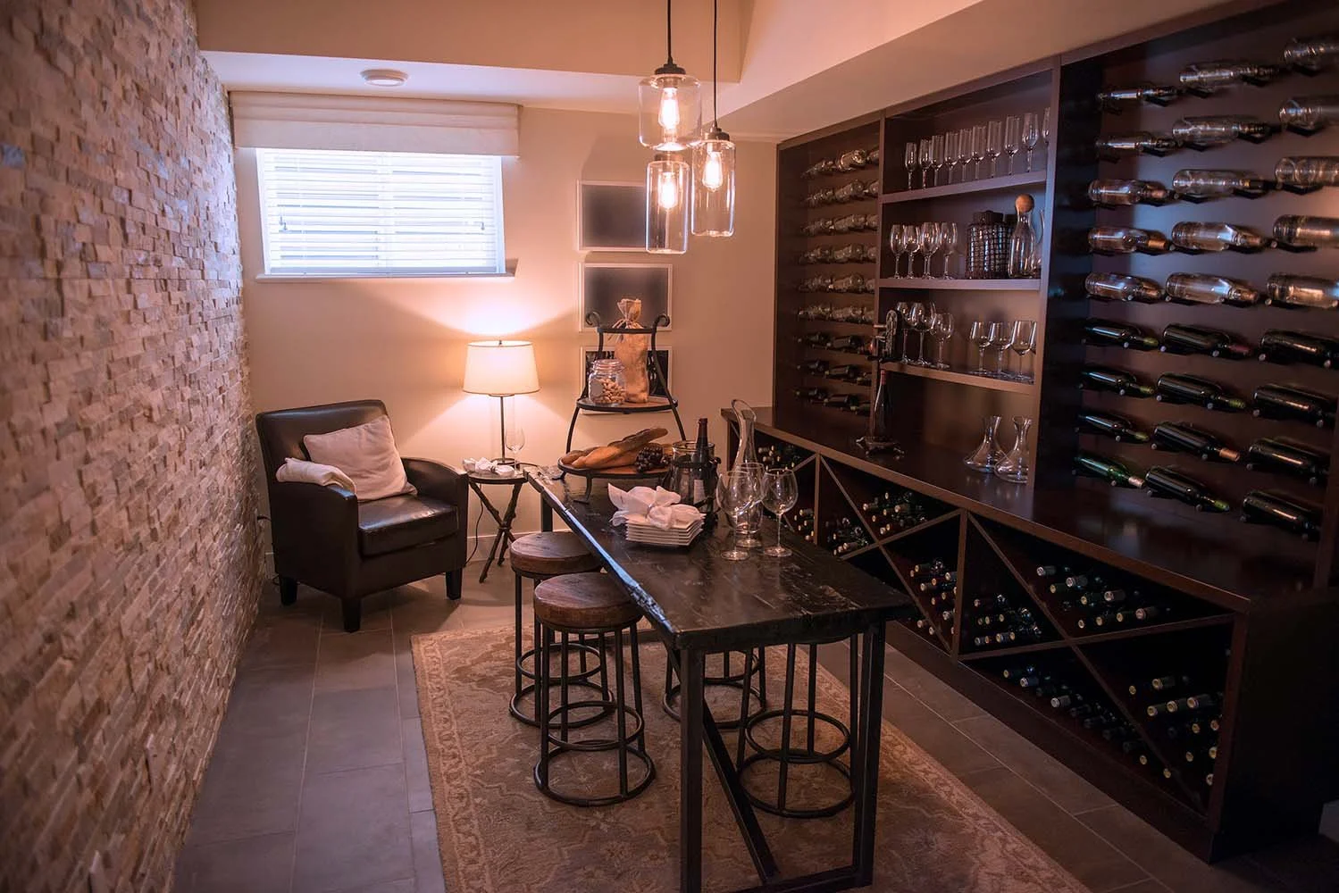 Small basement wine cellar with custom storage wall, lighting and furniture. Basement window shown.