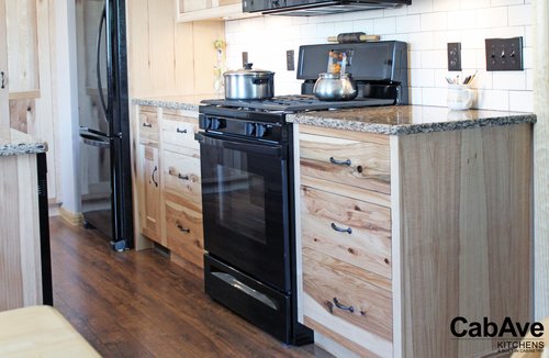 Modern kitchen with wooden cabinets, granite countertops, black appliances, and wooden floor.