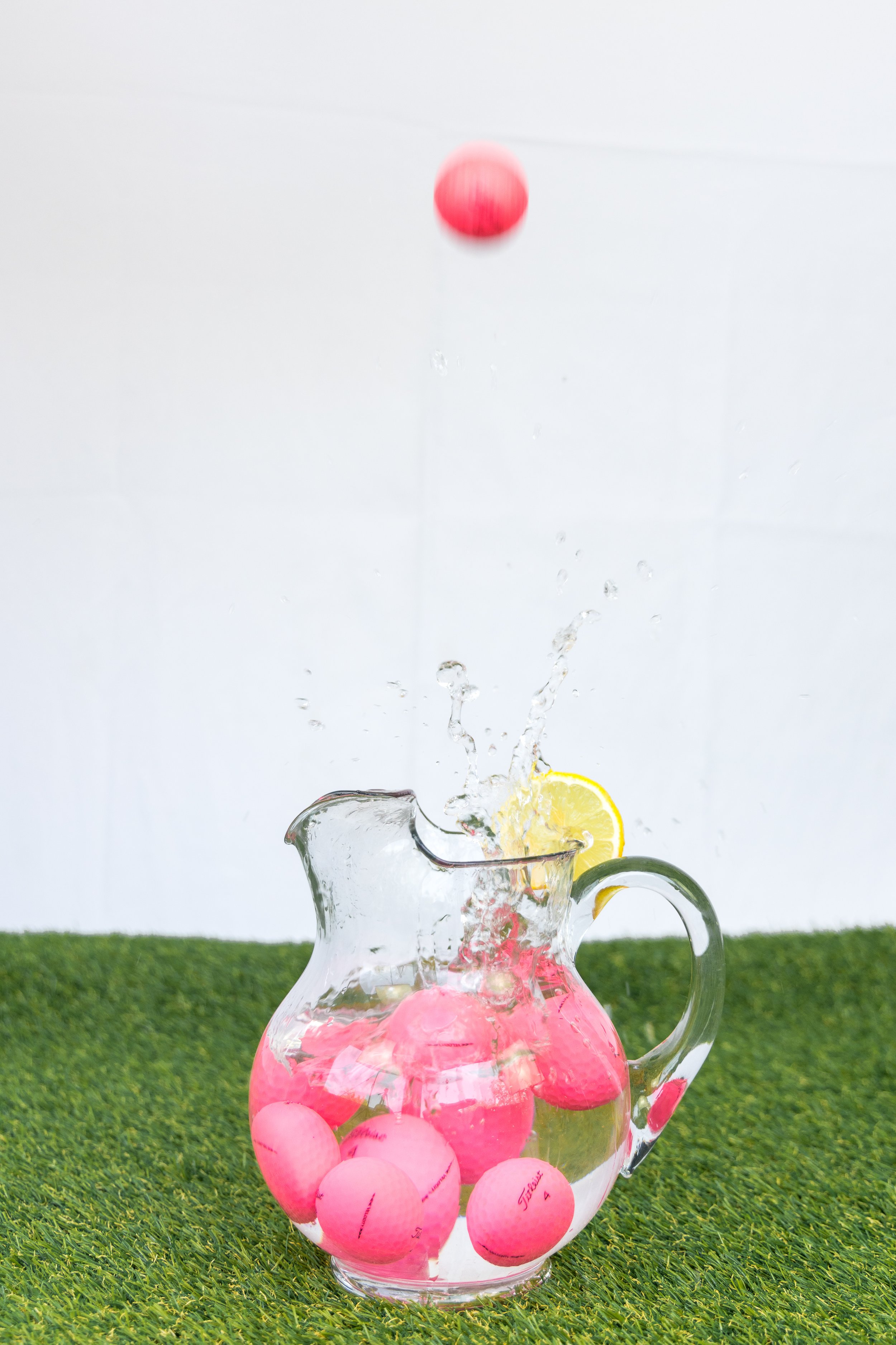  Colorful golf balls splashing into pitcher of water, 