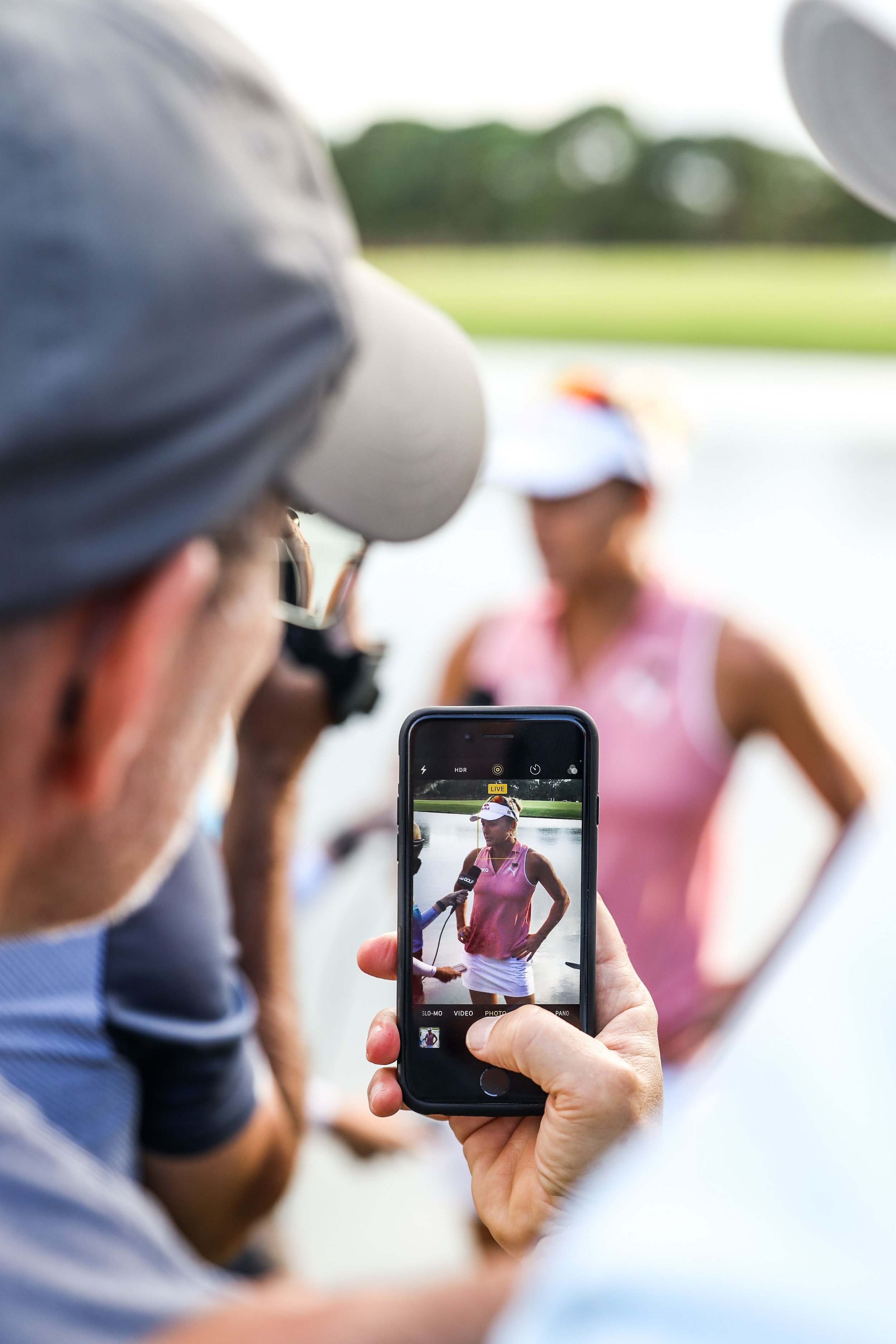  Spectator taking photo of female golf athlete being interviewed branded event photography. 
