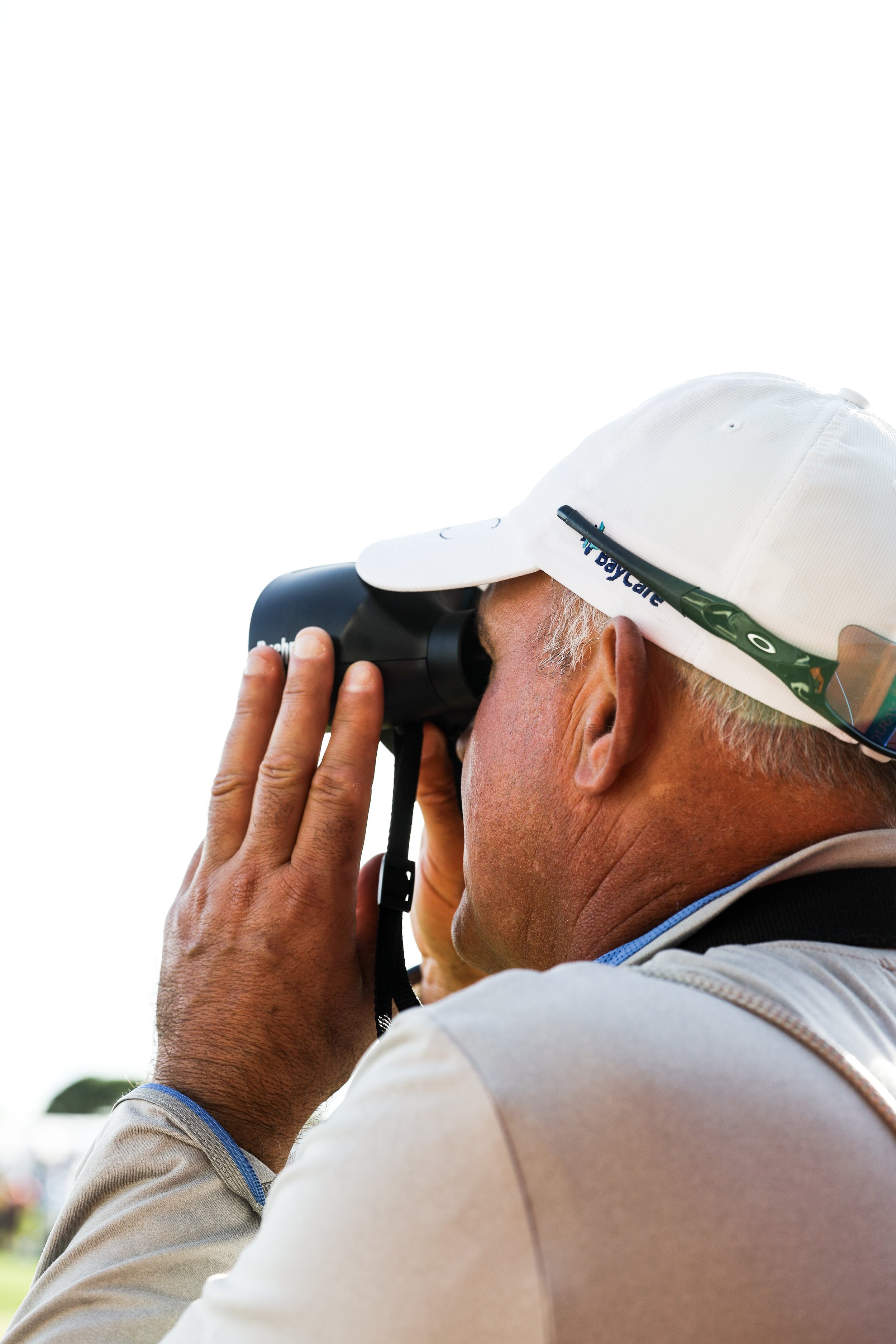  Spectator watching golf tournament through binoculars. 