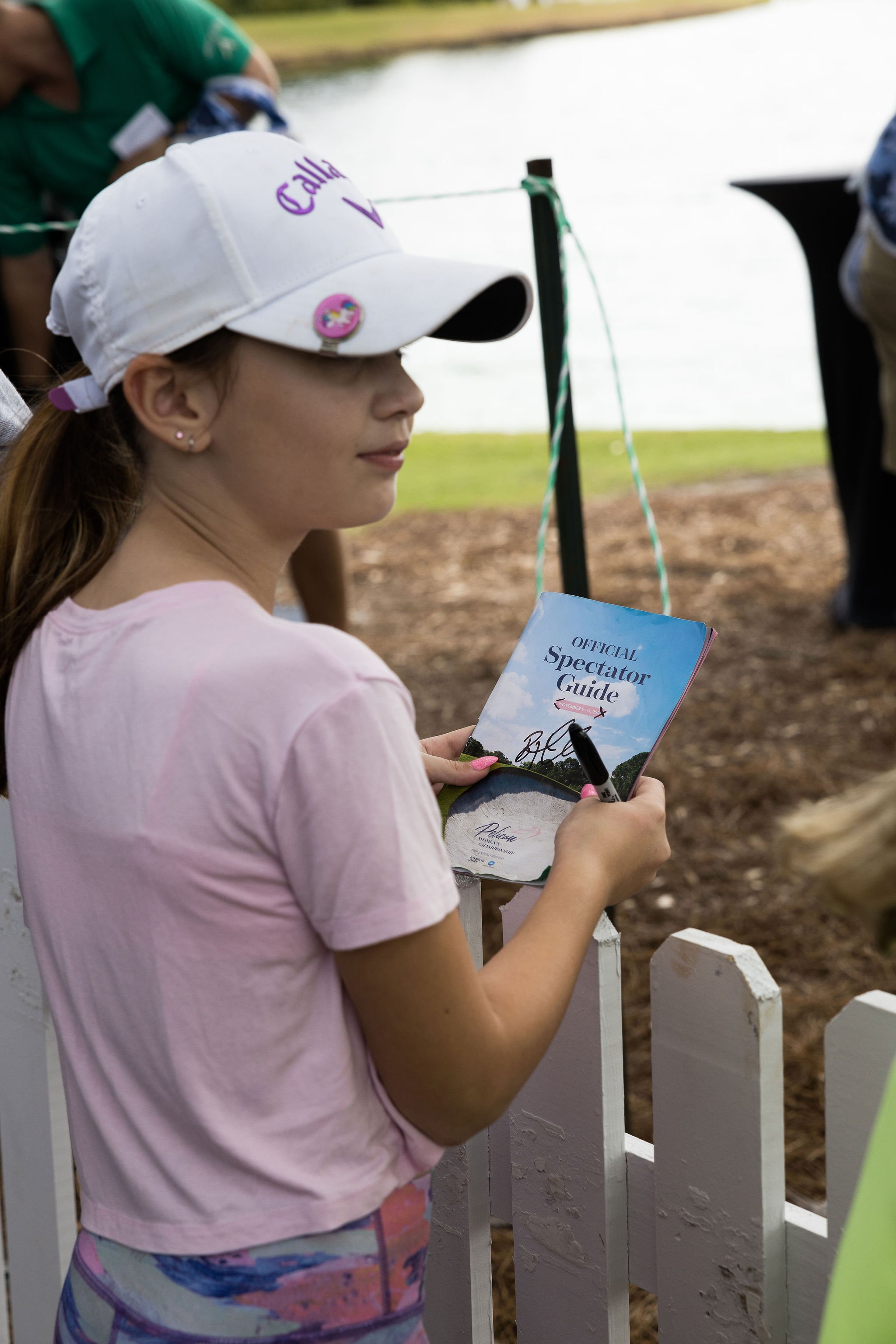  Girl standing holding Pelican Women's Championship spectator guide. 