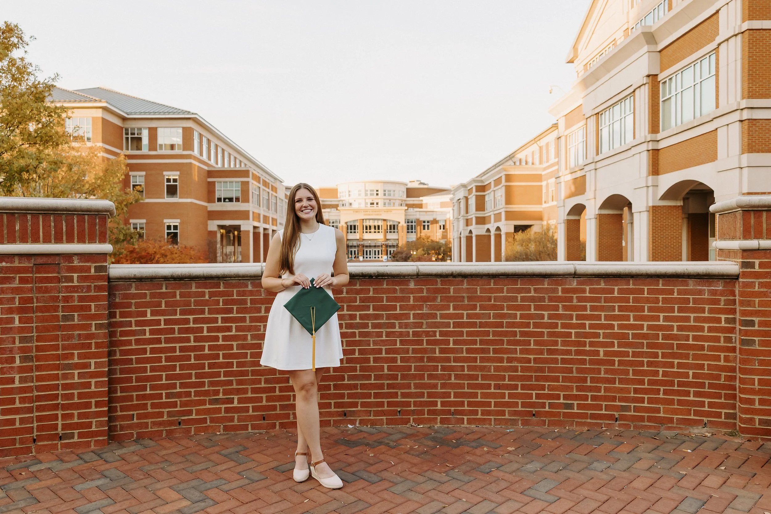 UNC Charlotte senior portrait of a chemistry student holding a graduation cap with the Union behind her.