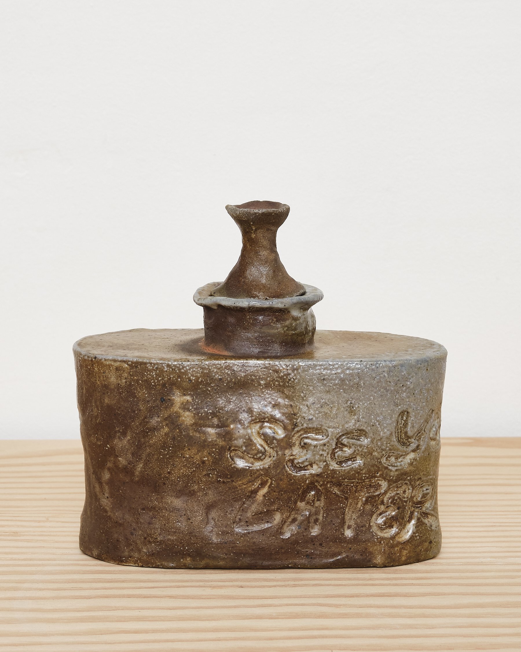 Clay sculpture resembling a gasoline can with a small chimney on top, inscribed with the words "See you later".