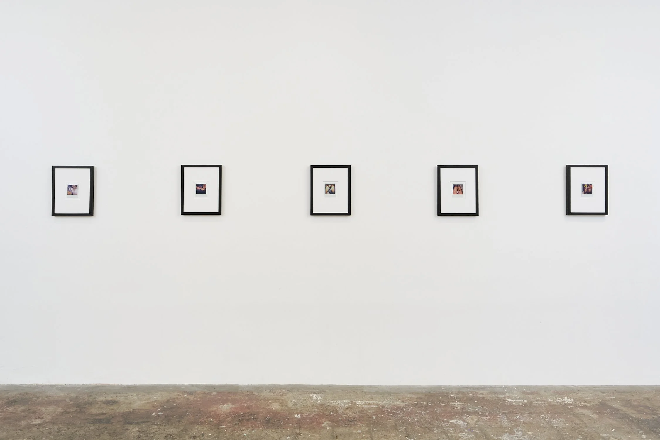 Gallery wall with five framed photographs displayed in a row on a white wall.