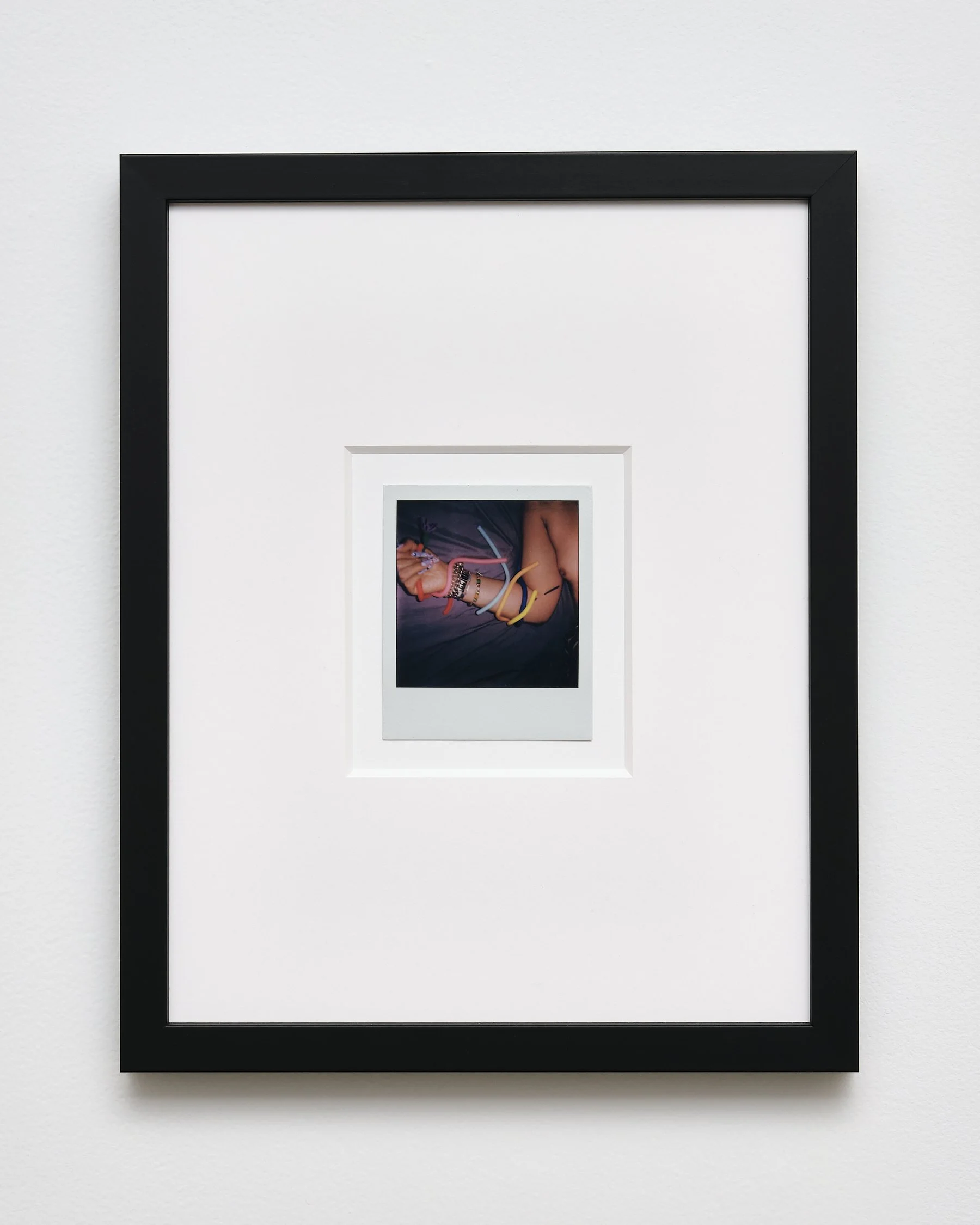 Close-up of a framed photograph on a white wall, showing a person holding colorful bands.