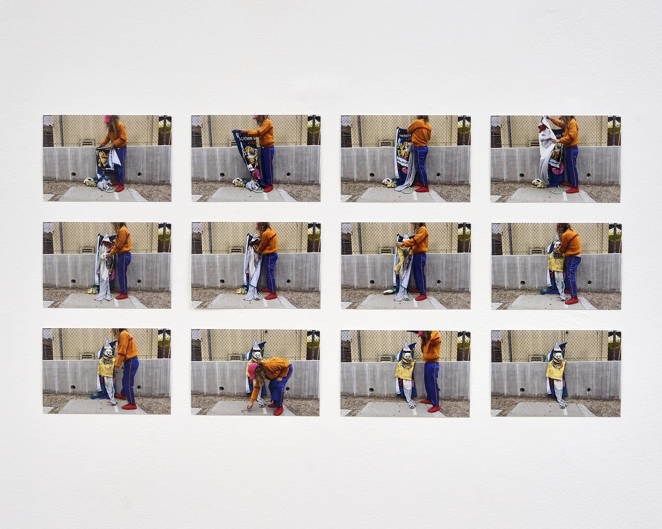 A series of nine photos shows a person with curly hair wearing a pink cap and an orange sweatshirt, putting on a clown costume in an outdoor setting behind a metal fence.