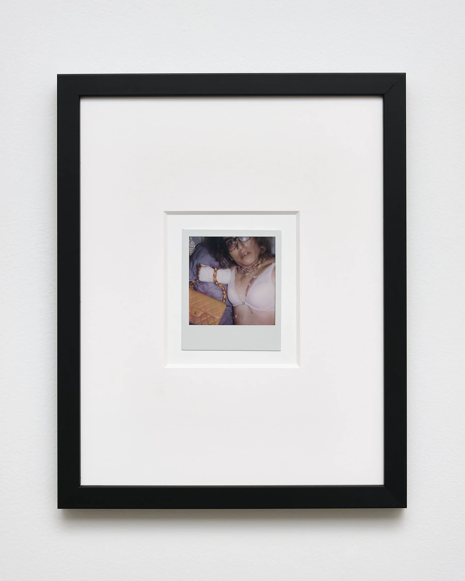 Framed photograph of a person with curly hair, wearing glasses and jewelry, lying down with her eyes open.