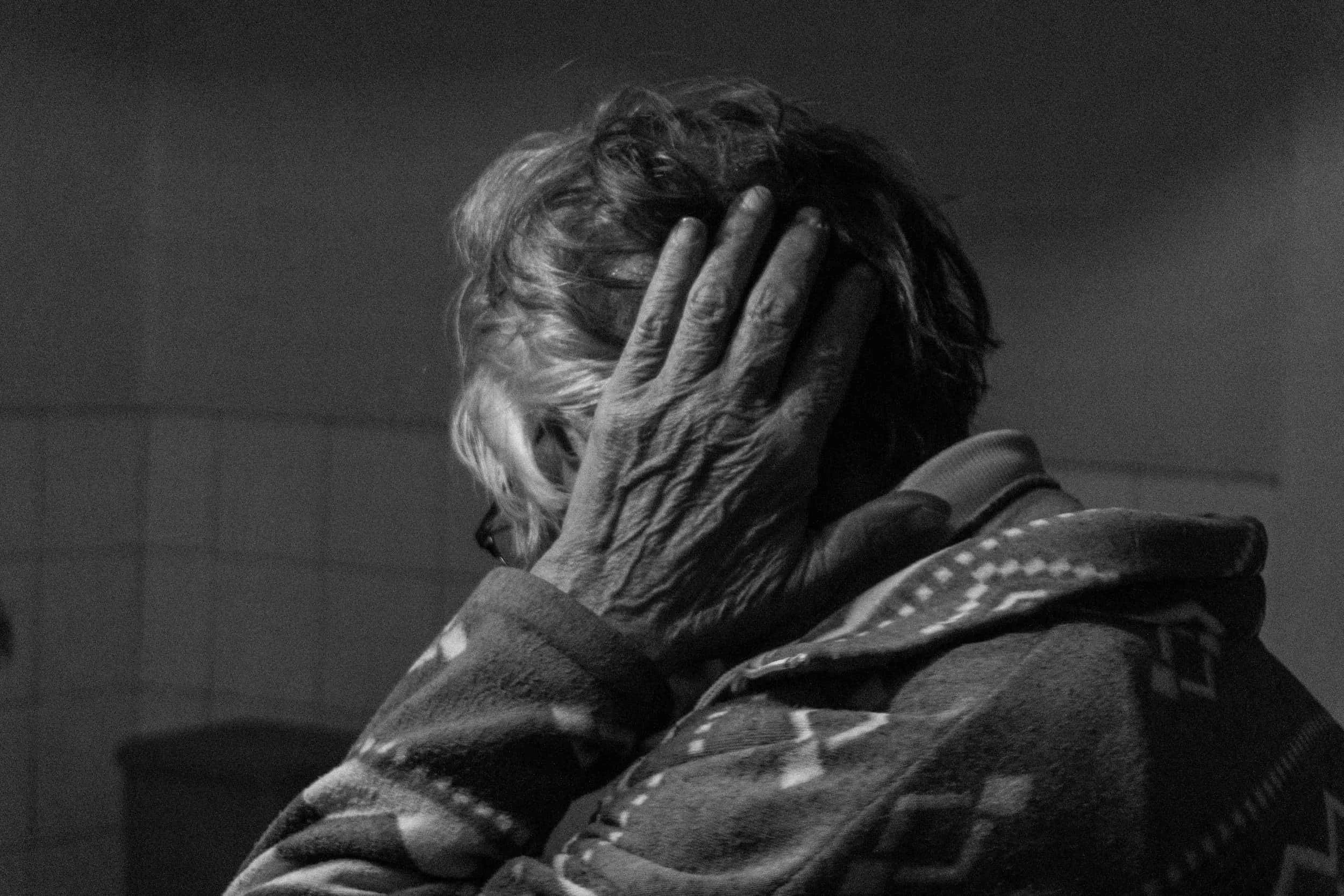 Elderly woman clutching her head with hand