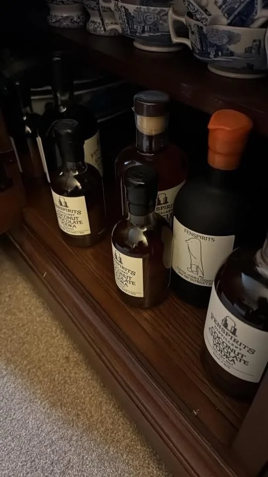Several bottles of spirits and liqueur on a wooden shelf, with some decorative bowls above.