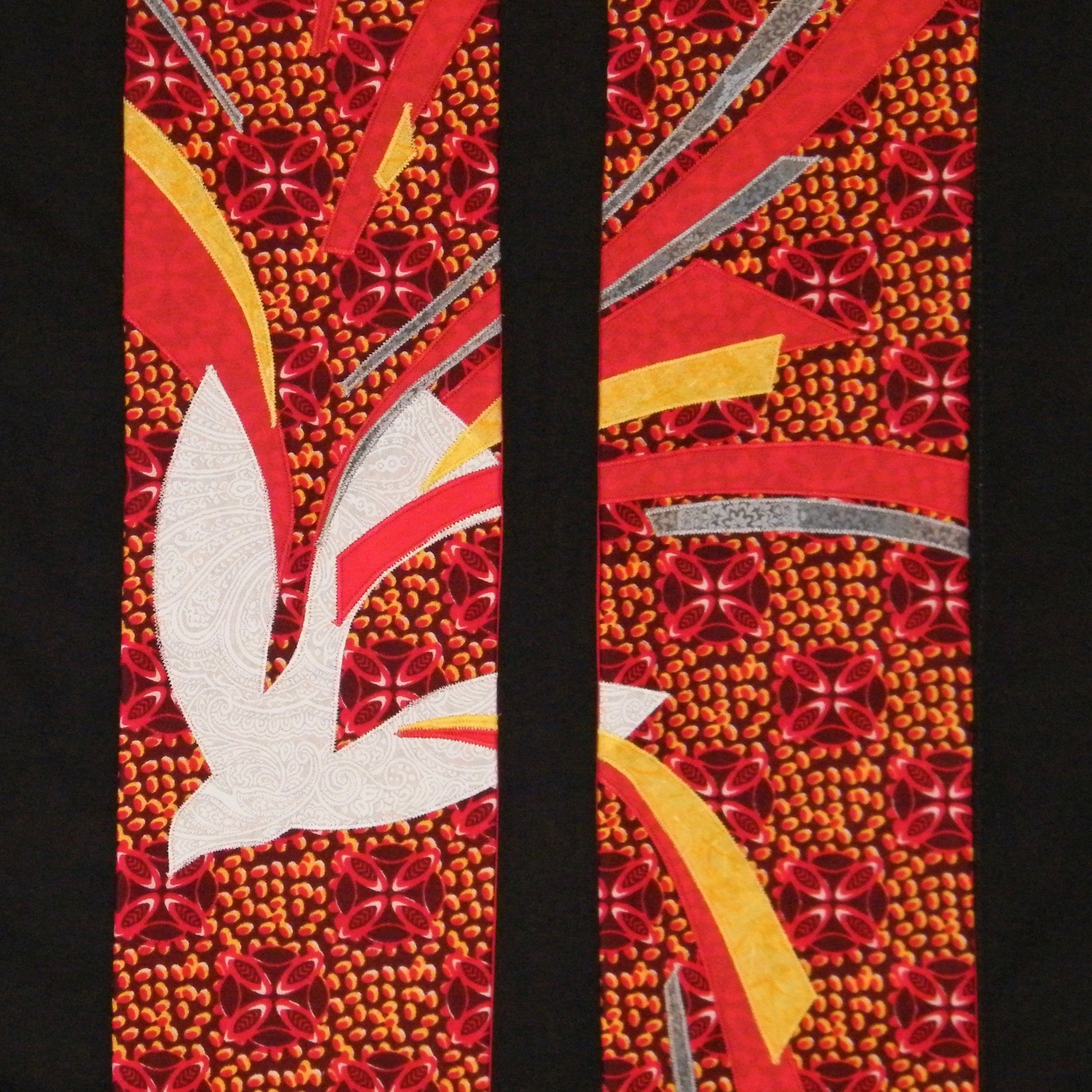 A detail of a red, clergy stole for Pentecost with descending dove and a rush of wind and movement by Carrot Top Studio.