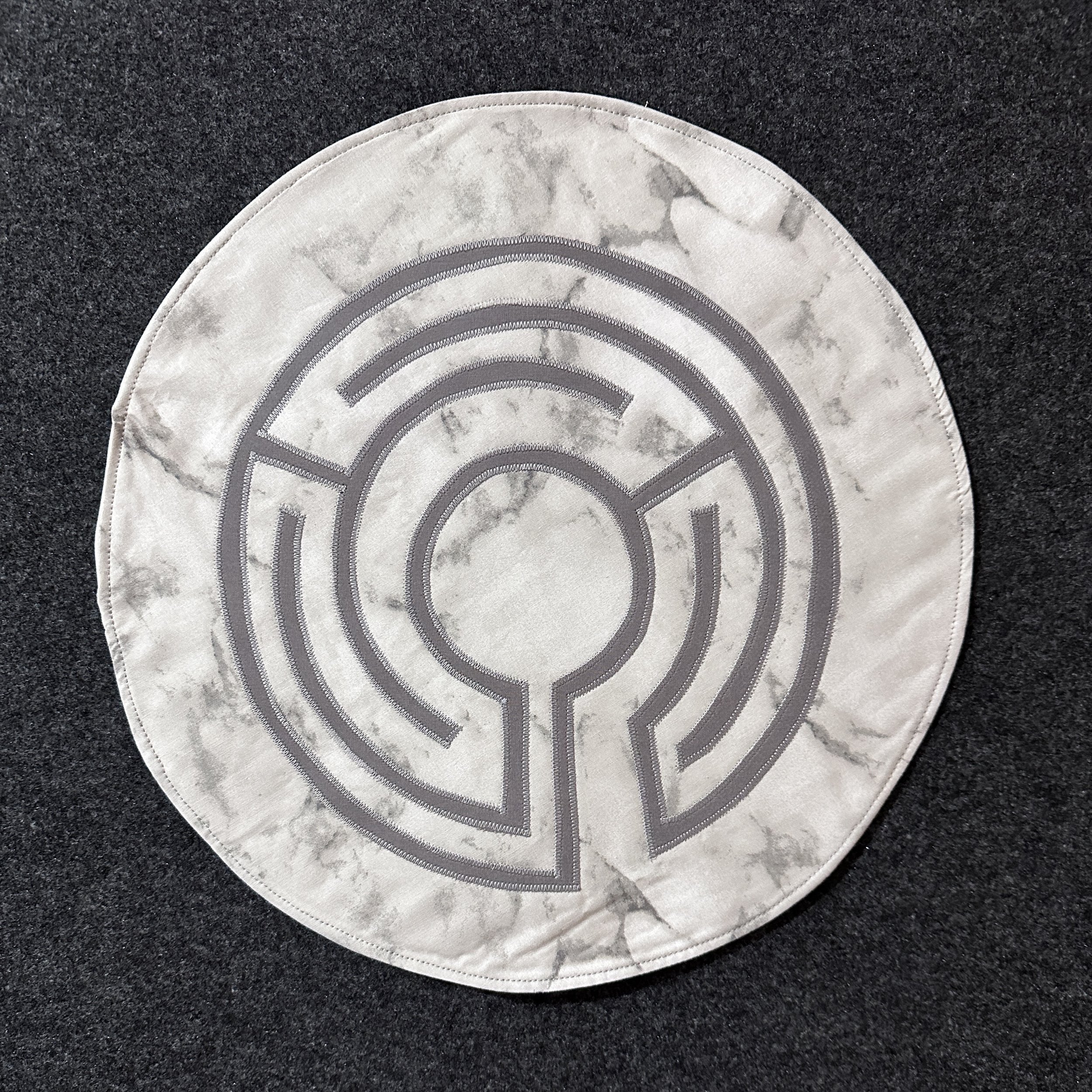 Portable 13-inch fabric finger labyrinth for tabletop use. Grey labyrinth on a light grey marbled background, perfect for prayer, meditation, and mindful travel.