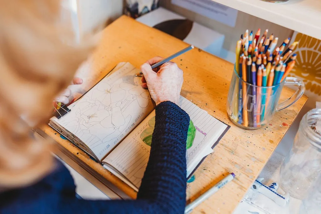 Artist Jenny sketching in book with colored pencils