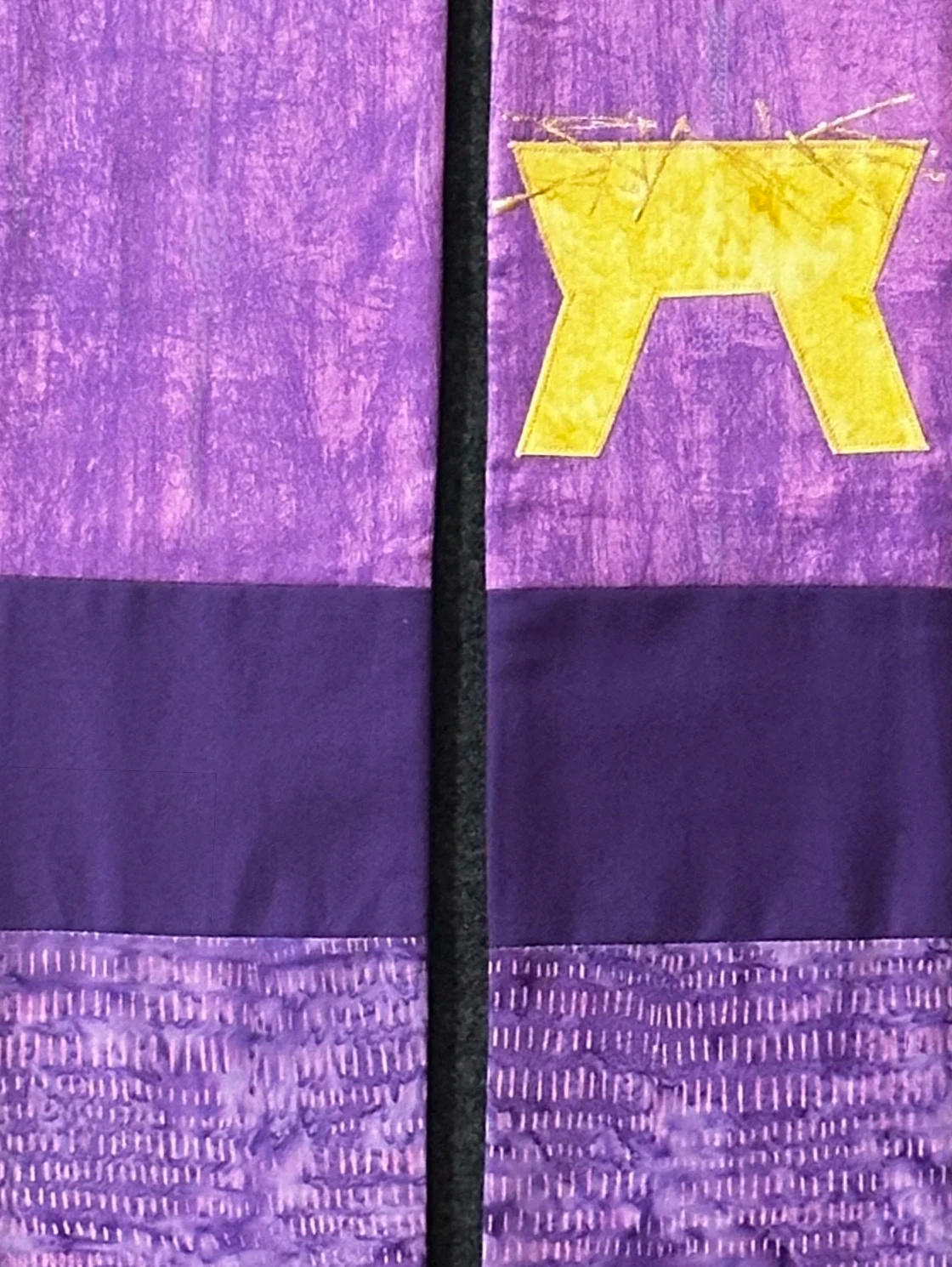 A creative purple stole for Advent with an empty manger appliquéd and hand painted in gold by Carrot Top Studio.