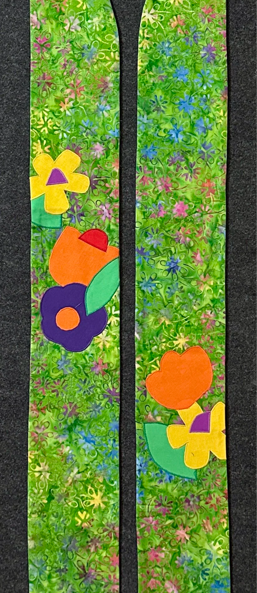 A green clergy stole for Ordinary Time with a vibrant bank background and bright colored blooming flowers and leaves.