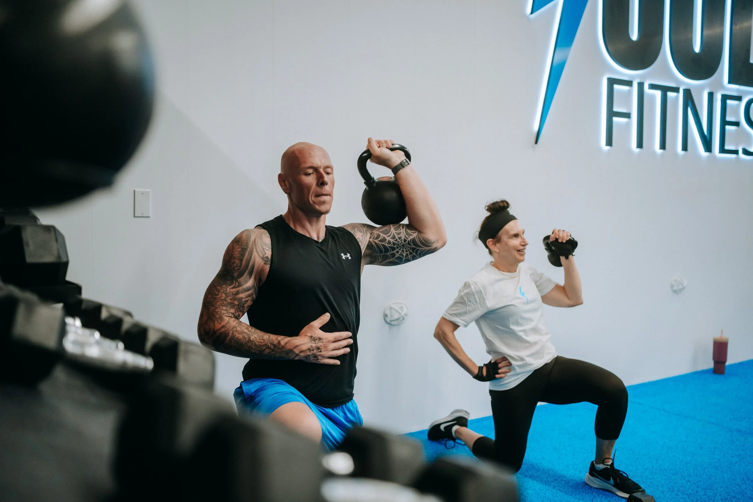 Jolt Fitness members exercising overhead press for upper body and core strength