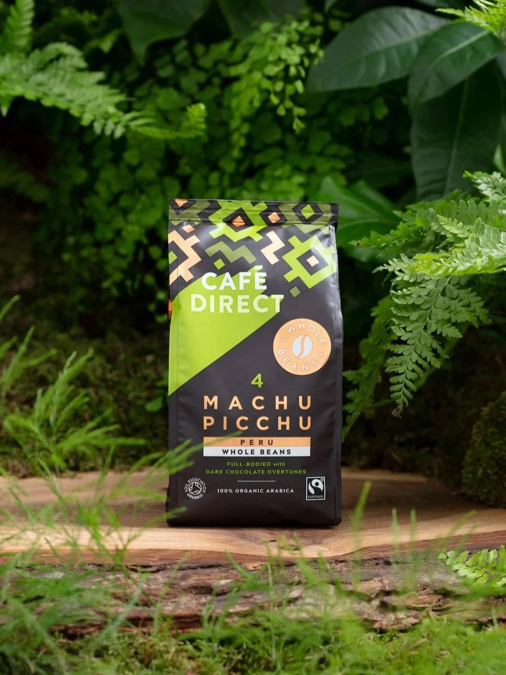 Package of Cafe Direct Machu Picchu Peru whole beans coffee in an outdoor garden setting.