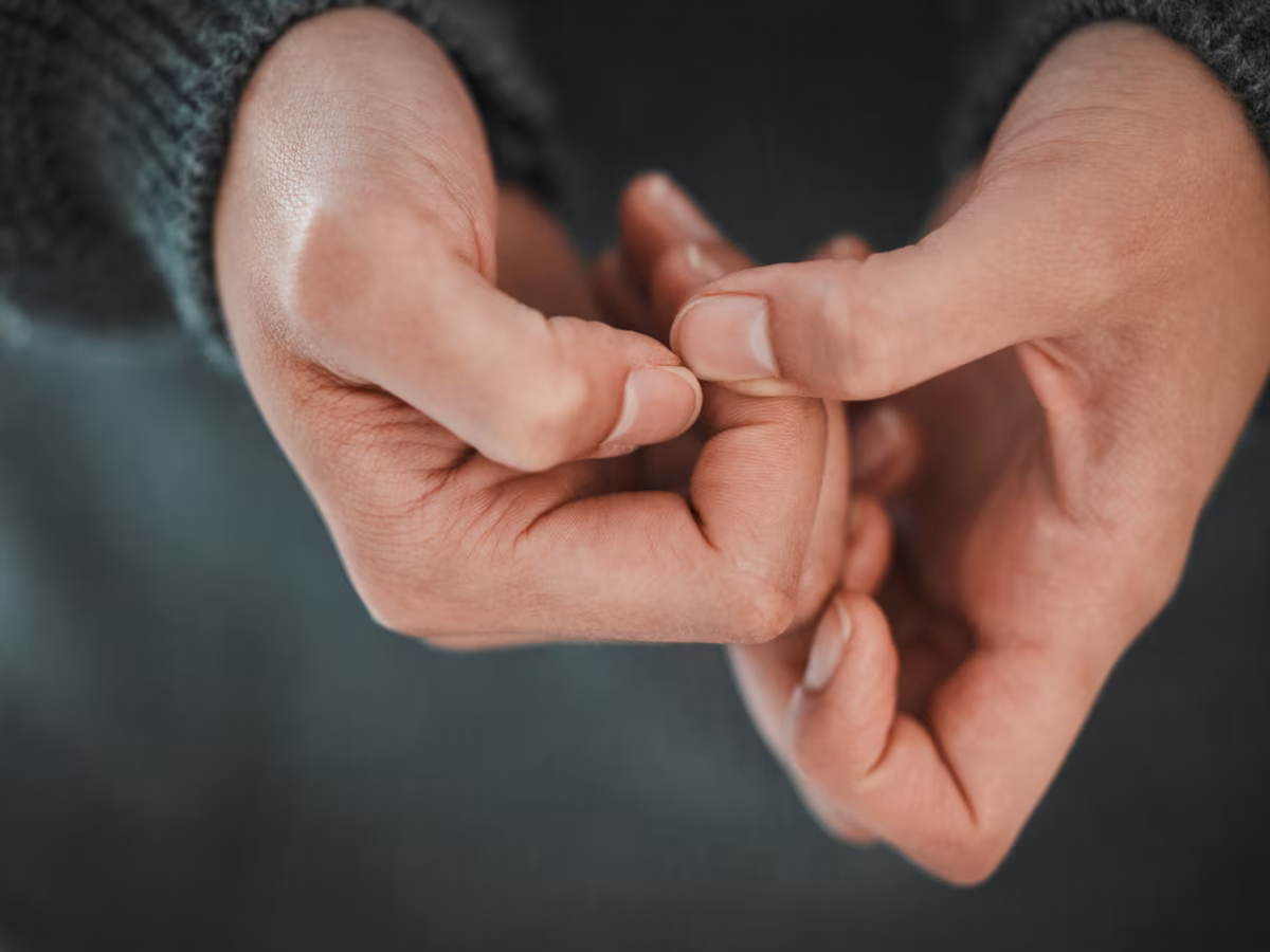 A close-up of two hands touching, with fingers interlocked.