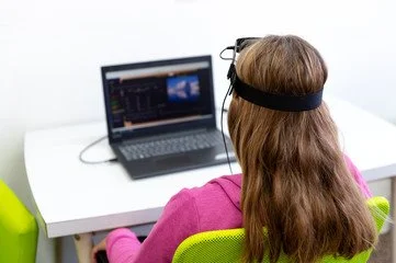 woman viewing laptop with neurofeedback equipment