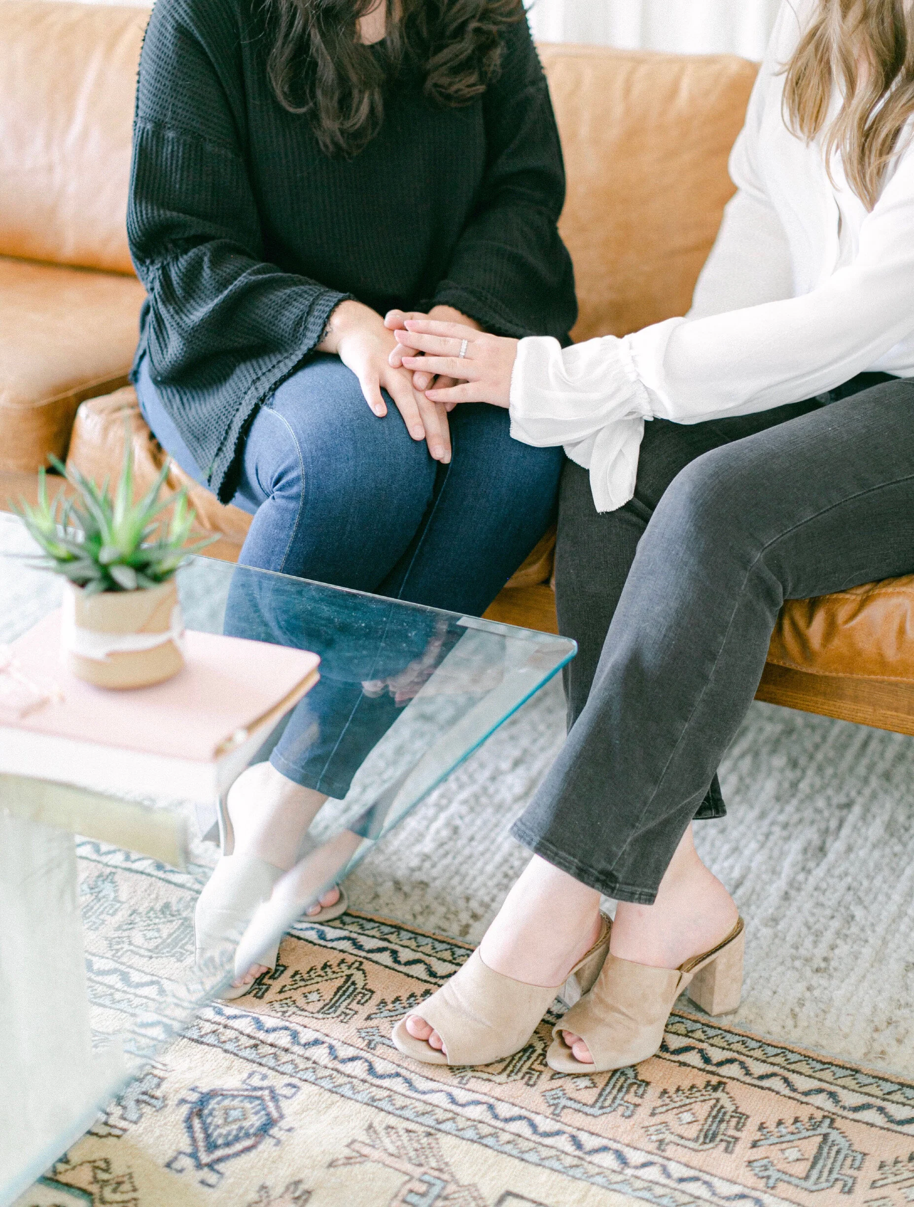 Two people engaged in a supportive counseling session on a leather couch, demonstrating the connection and safety prioritized at our Denver therapy practice.