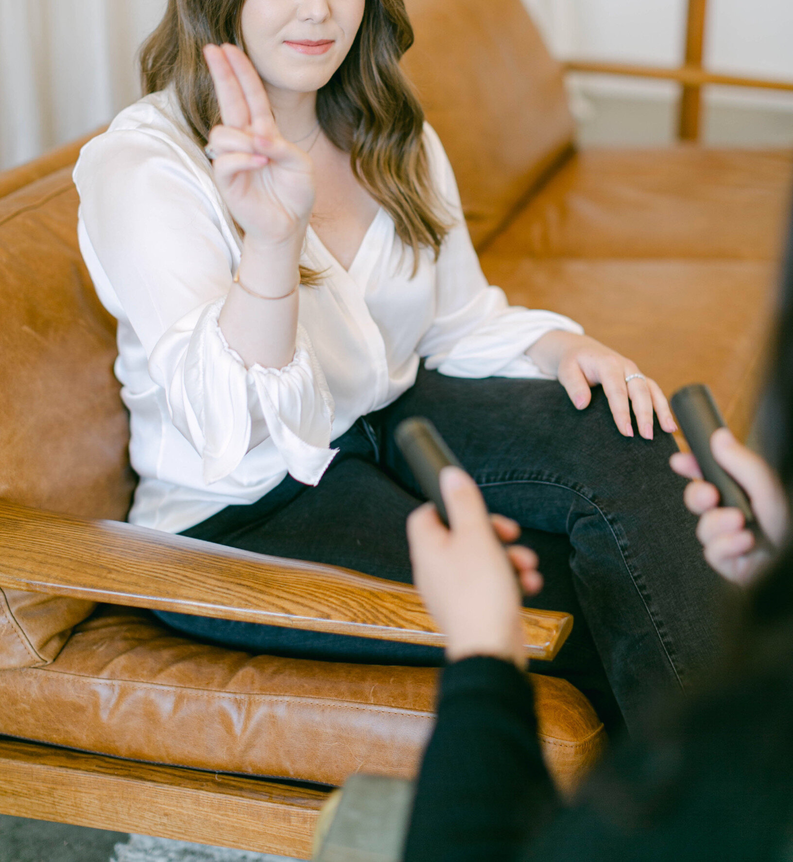 Chadley Zobolas facilitating an EMDR session by using bilateral hand movements while seated in a comfortable leather therapy office chair.