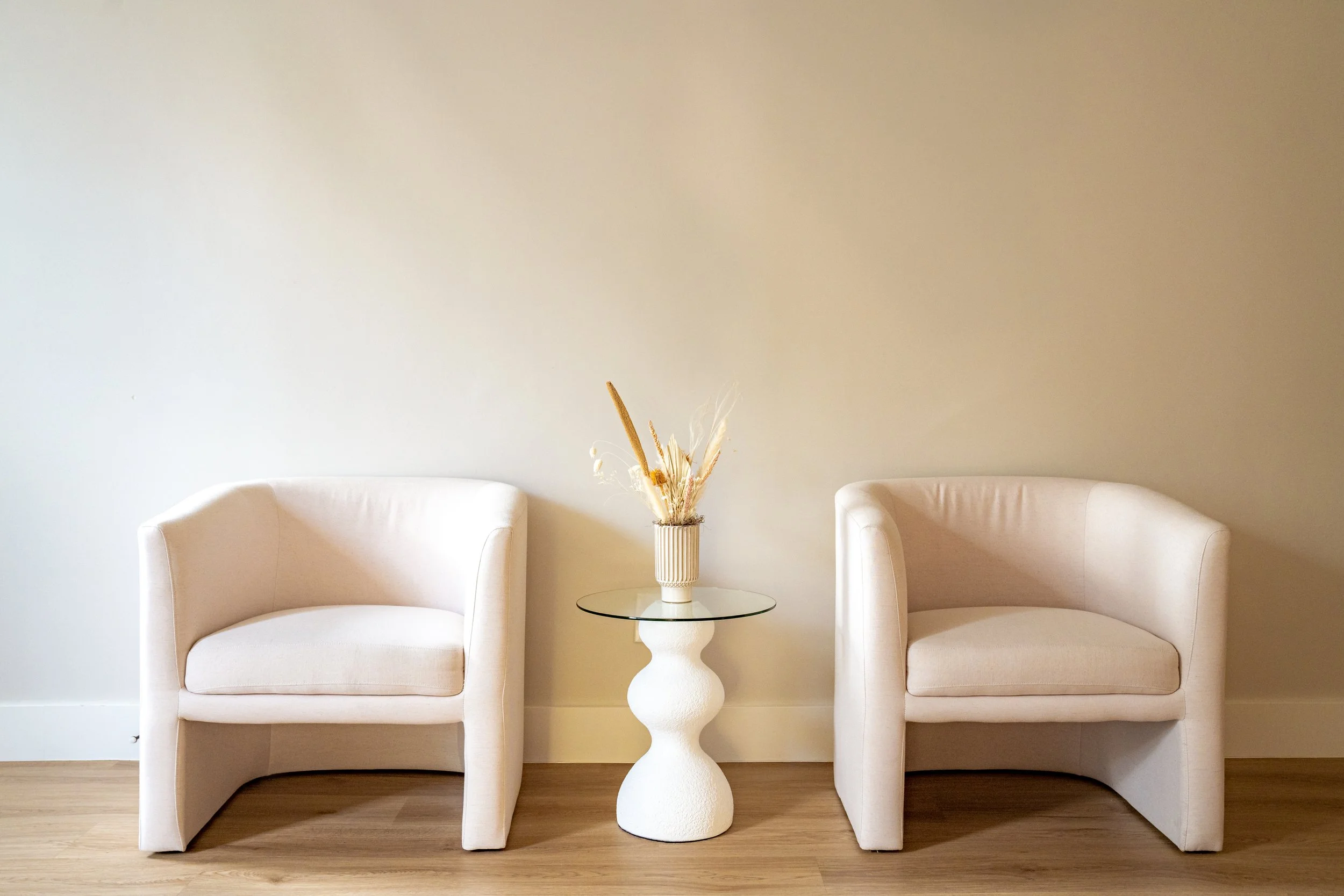 A comfortable cream-colored chair and side table in our Denver therapy office lobby, designed to be a calm and welcoming space to wait before your session.