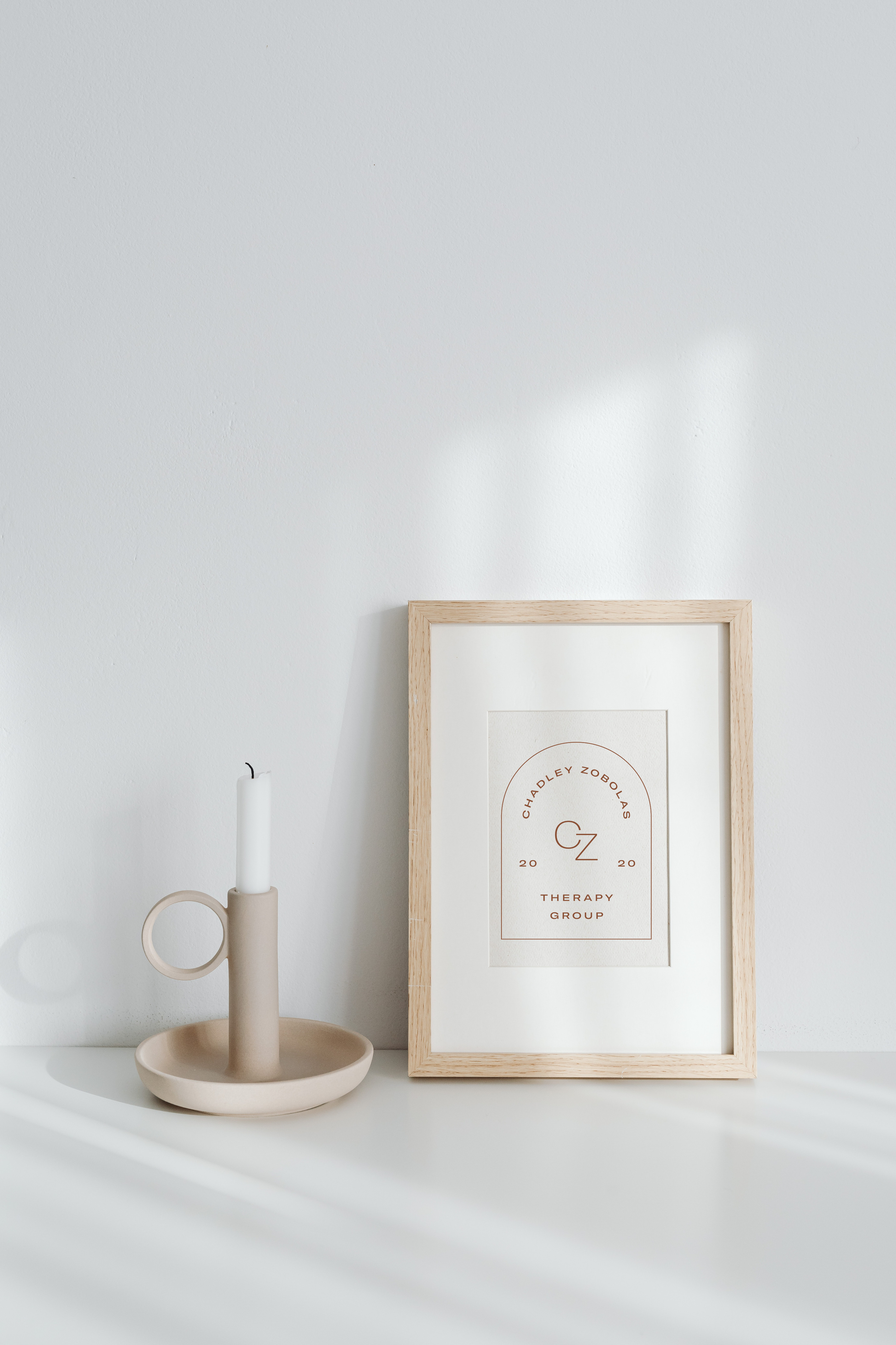 The CZTG therapy logo in a frame next to a candle, symbolizing the intentional and focused environment provided for EMDR therapy in Denver.