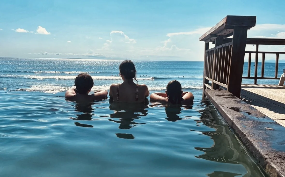 Lisa Kern and her two sons looking out at the ocean from an infinity pool during their family travels.